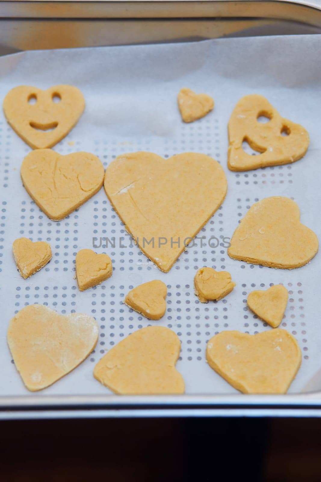 Cookies cut in dough on baking tray. Taking part in baking workshop. Baking classes for children, aspiring little chefs. Learning to cook. Combining and stirring prepared ingredients. Real people, authentic situations