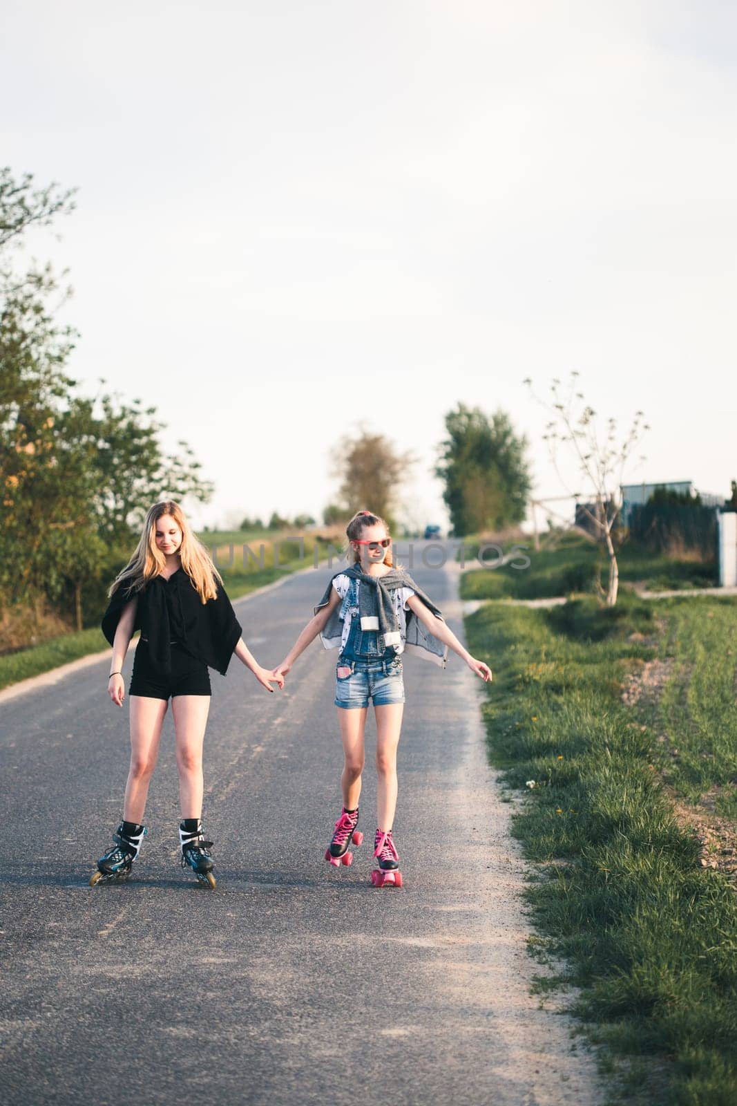 Teenage smiling happy girls having fun rollerskating, spending time together on summer day