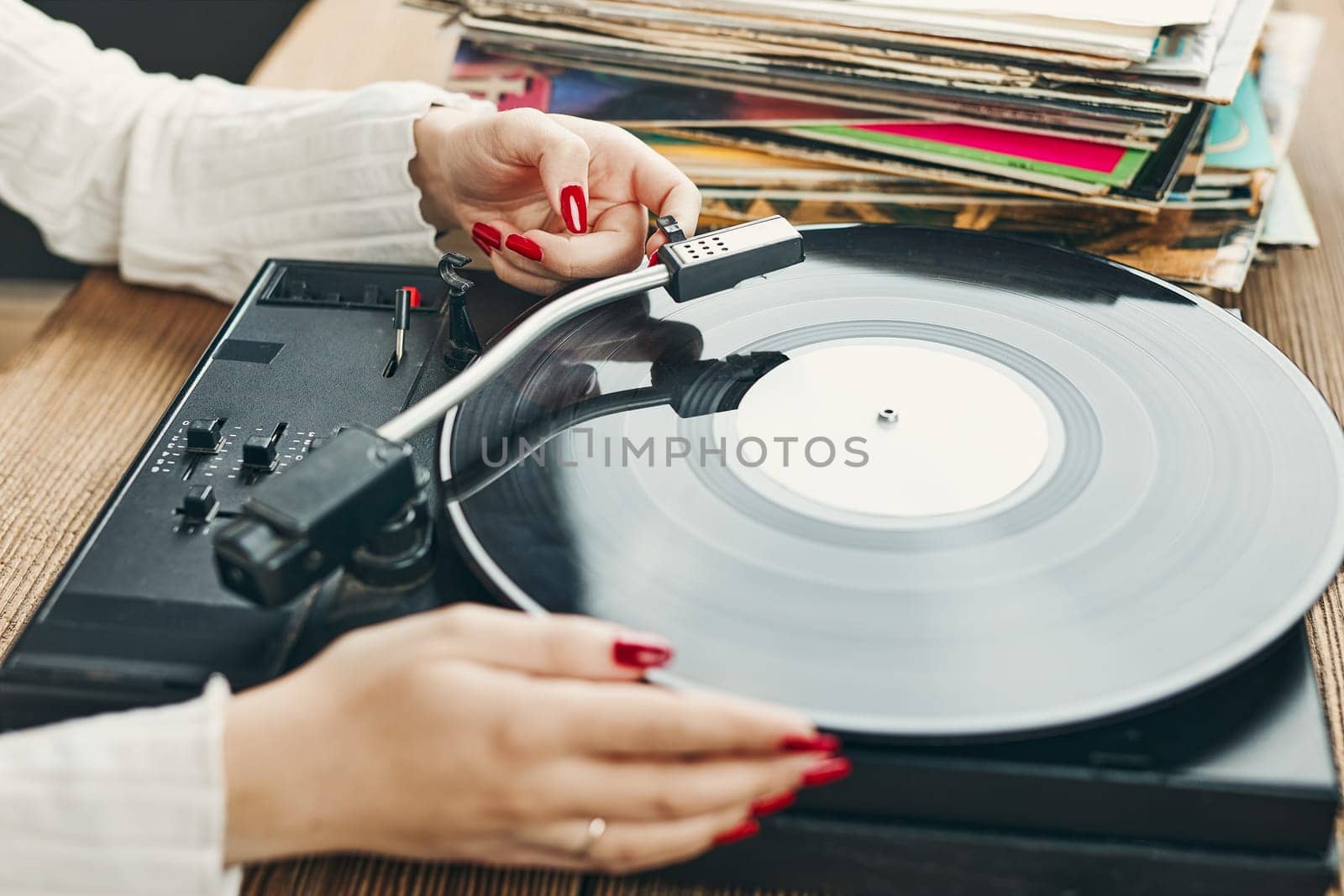 Young woman listening to music from vinyl record player. Playing music on turntable player. Female enjoying music from old record collection at home. Stack of analog vinyl records. Retro and vintage music style. Music Passion and hobby