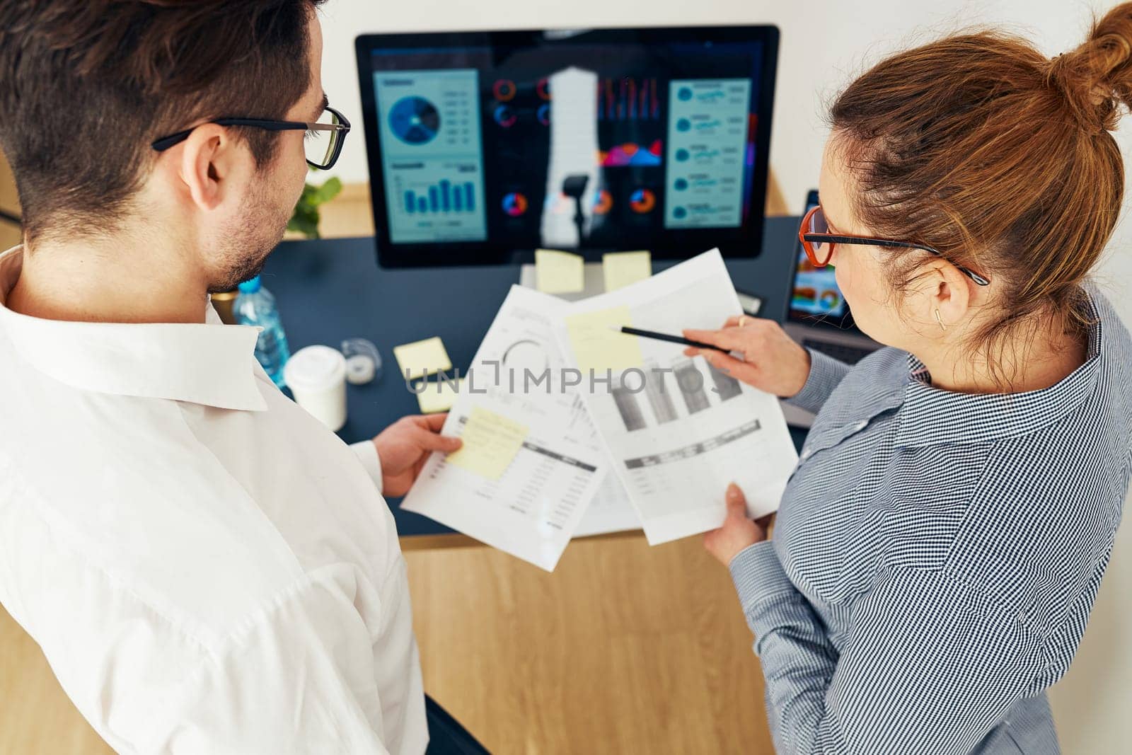 Business colleagues discussing financial data working together in office. People entrepreneurs working with charts and tables on computer. Two people working together. Workmates talking about project