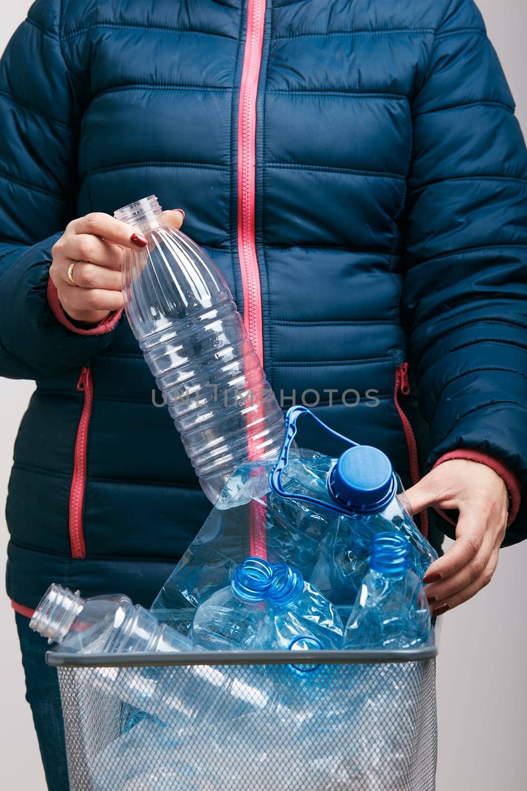 Woman throwing out used plastic bottles and packagings in trash bin. Collecting empty plastic squashed bottles in blue bag. Plastic waste to recycling. Concept of plastic pollution and too many plastic waste