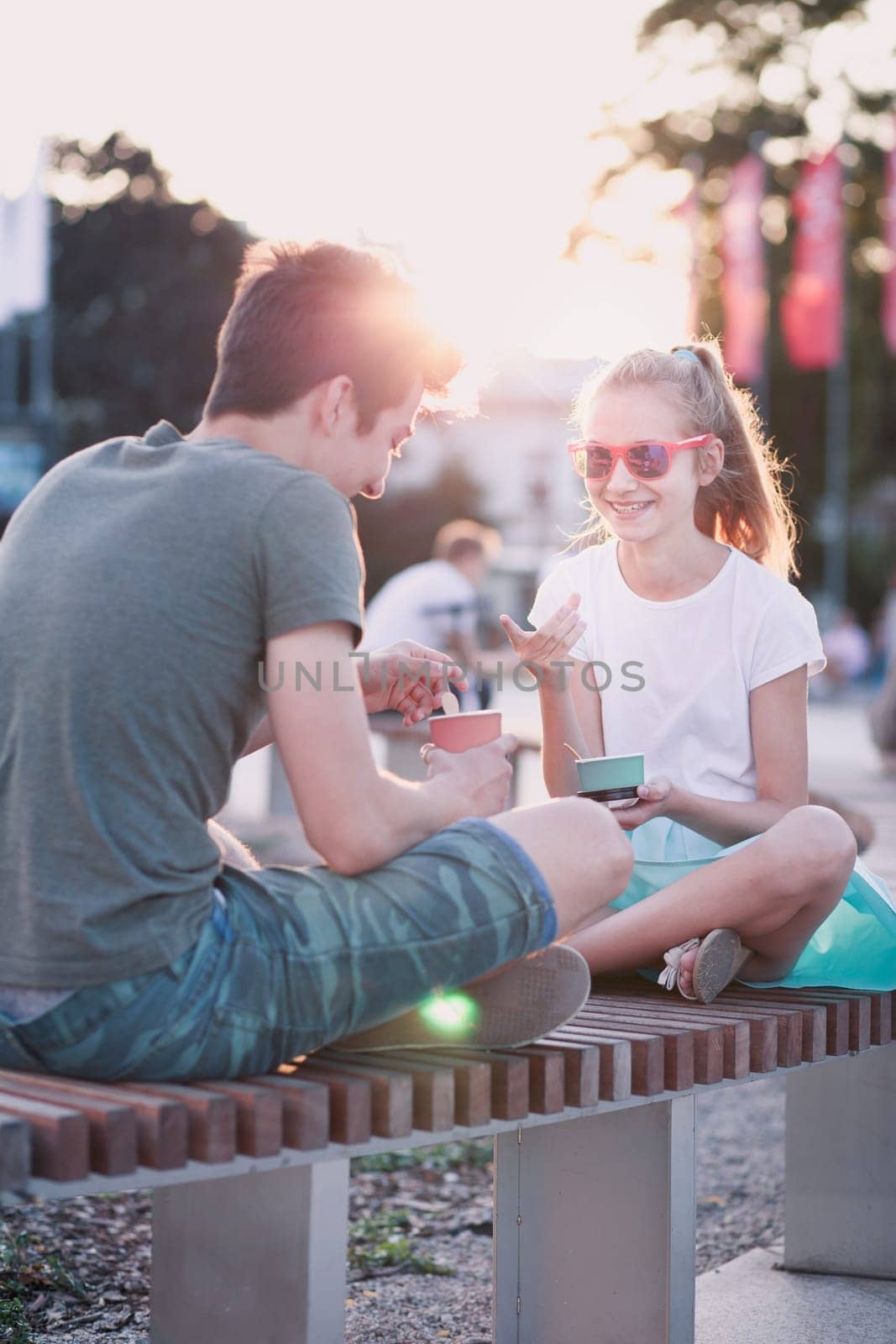 Girl and boy spending time together in the city centre eating ice cream on a summer day