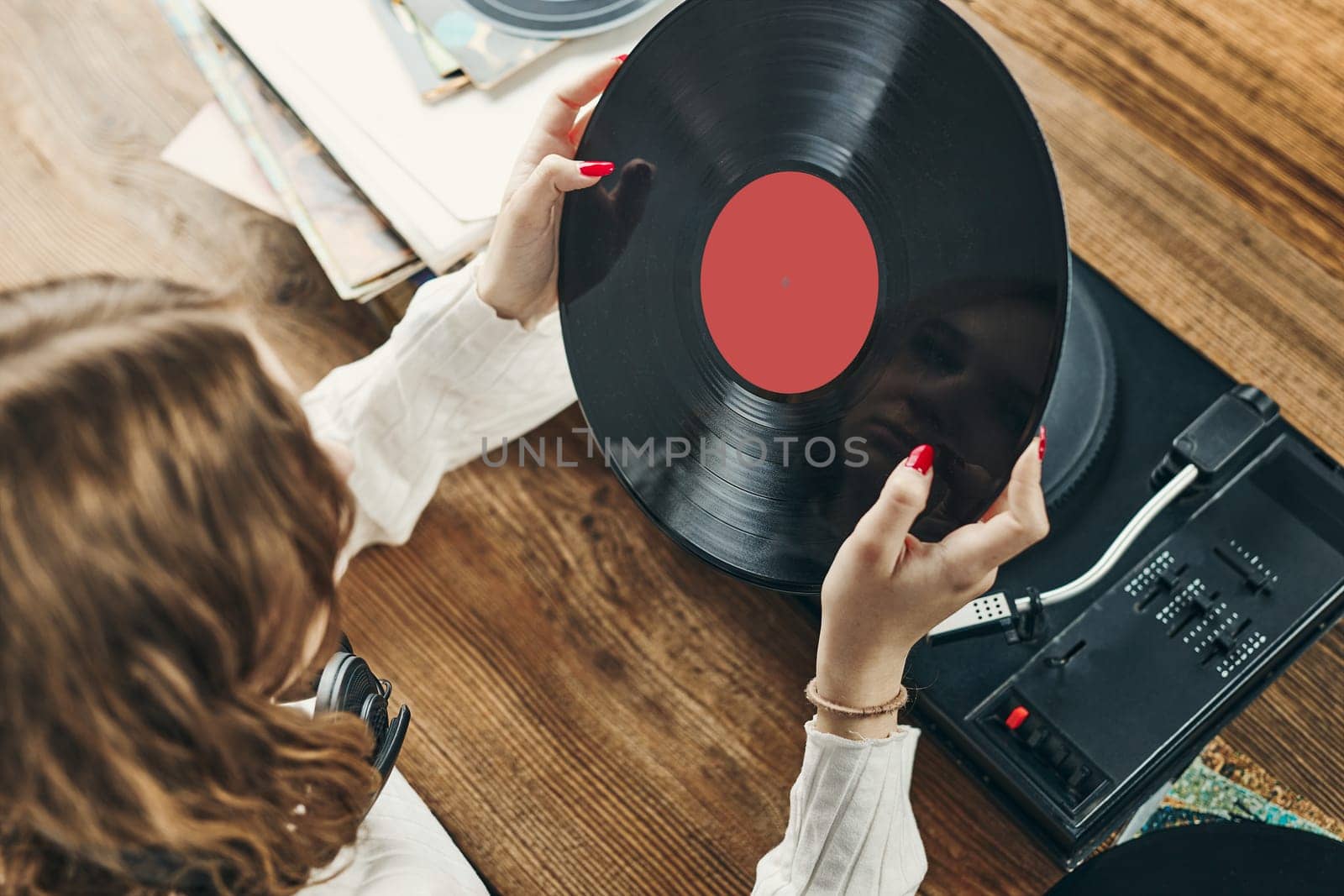 Young woman listening to music from vinyl record player. Playing music on turntable player. Female enjoying music from old record collection at home. Stack of analog vinyl records. Retro and vintage music style. Music Passion and hobby