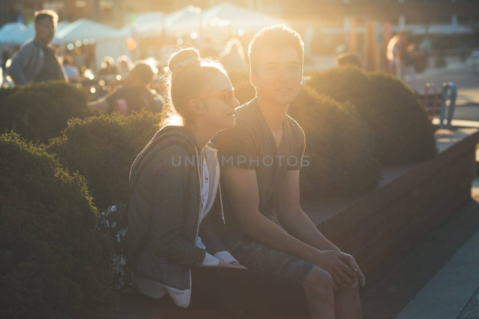Couple of friends, teenage girl and boy,  having fun together, sitting in center of town, spending time together