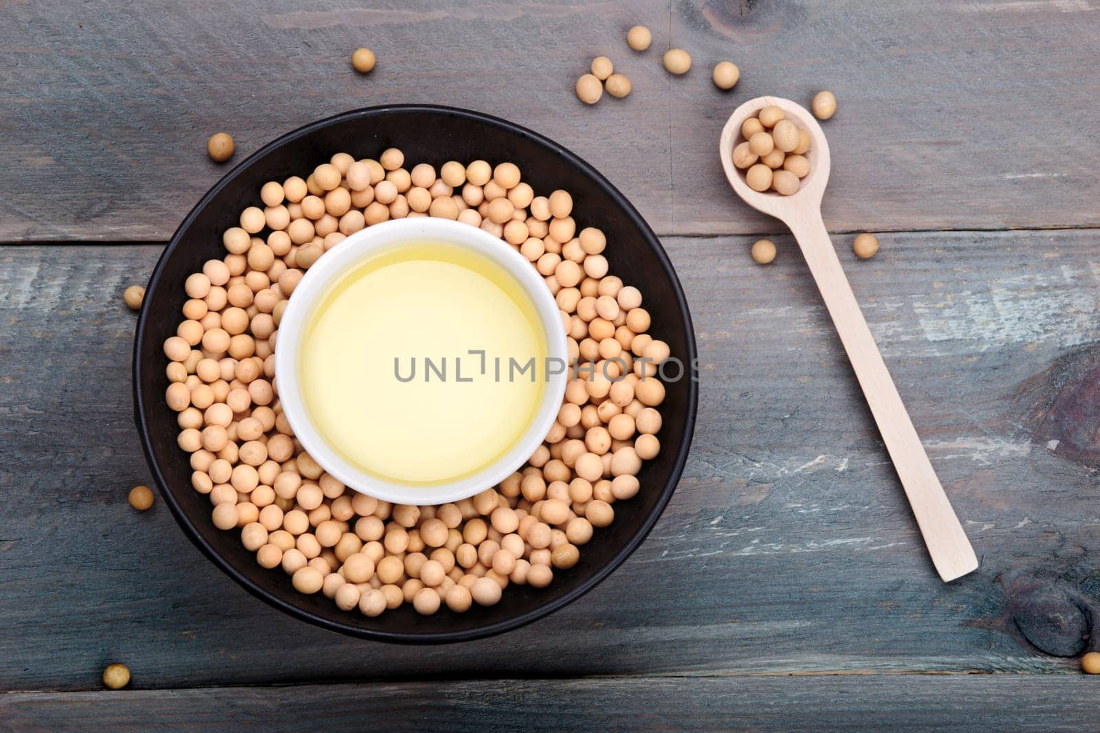 Soy beans and soy oil in bowls on wooden table
