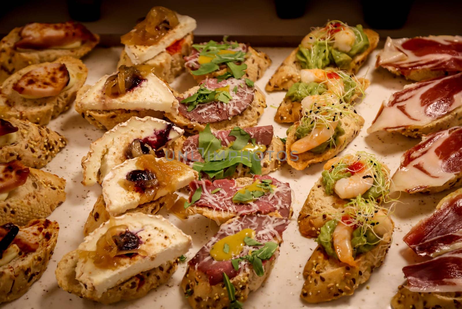 Lots of bites with cheese and ham in a tapas bar.