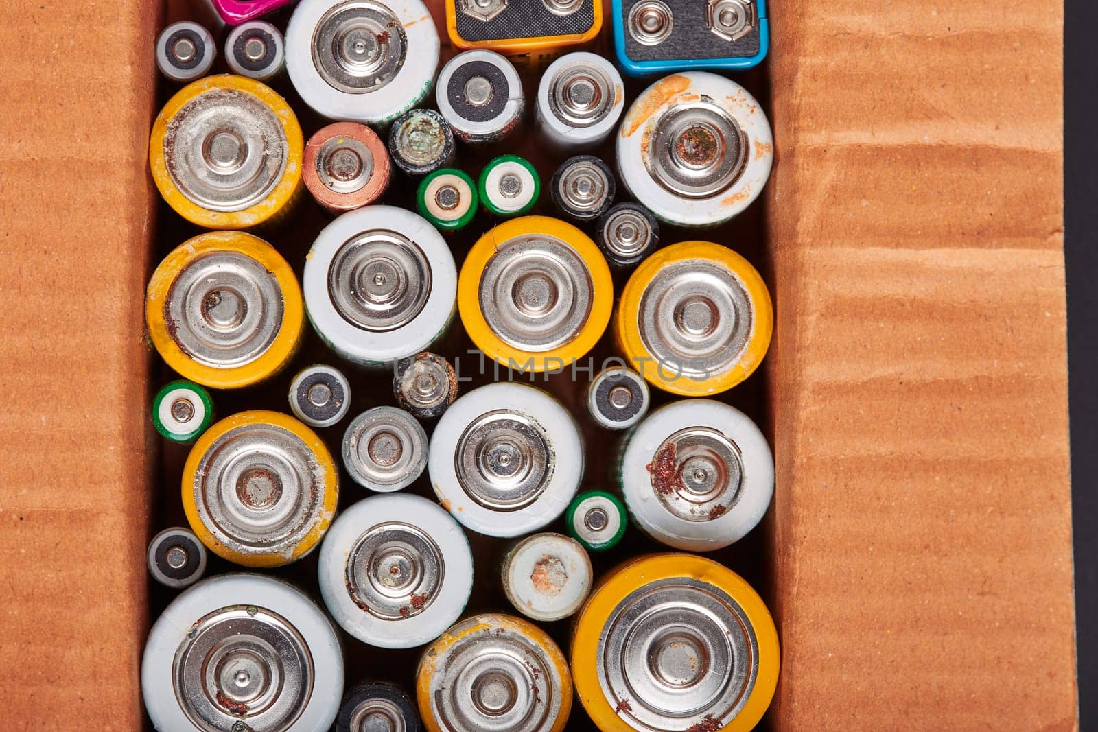 Discharged batteries in cardboard box. Collecting used batteries to recycle. Waste disposal and recycling. Copy space for text