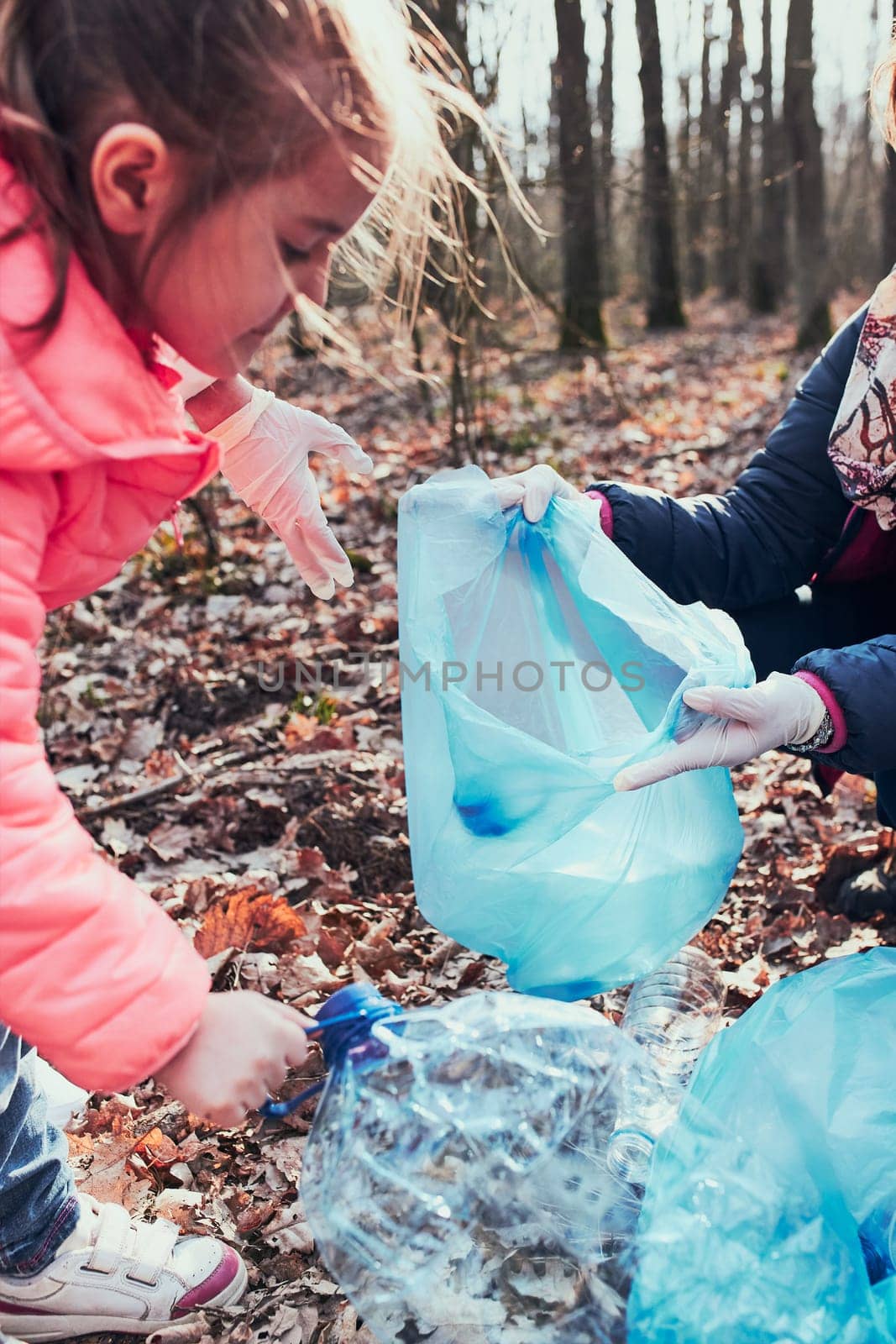 Family cleaning up a forest. Volunteers picking plastic waste to bags. Concept of plastic pollution and too many plastic waste. Environmental issue. Environmental damage. Responsibilitiy for environment. Real people, authentic situations