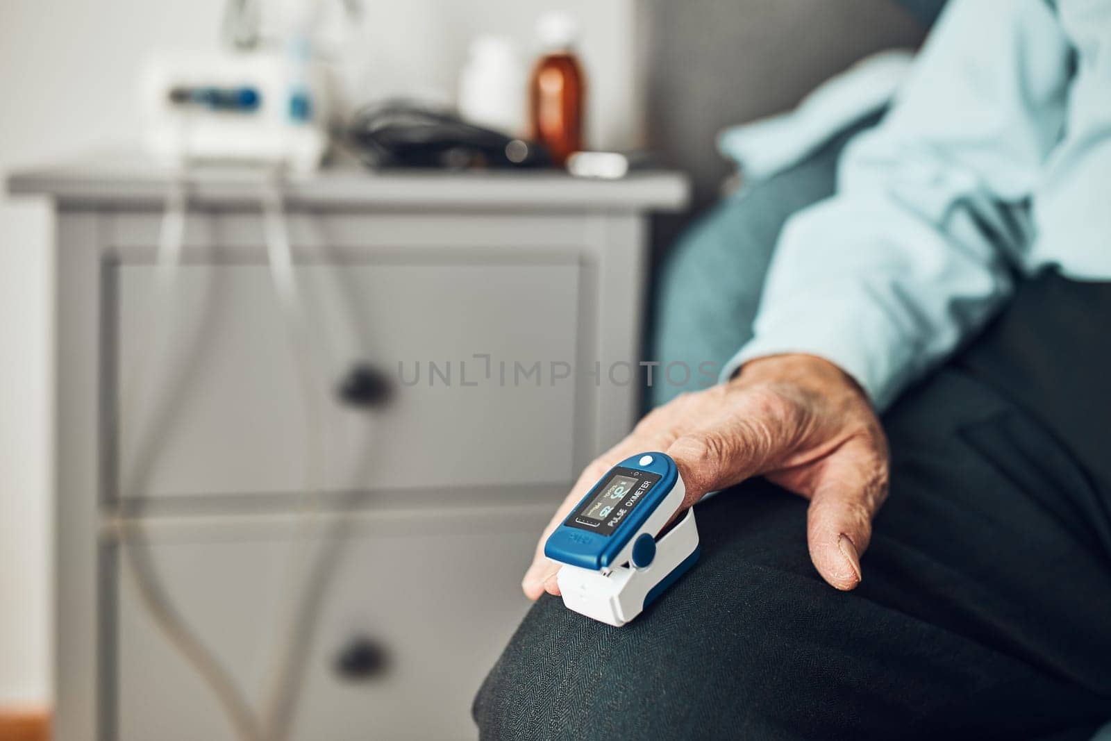 Senior man measuring the degree of oxygen saturation of the blood and heart rate at home using pulse oximeter. Home treatment of virus. Checking health condition. Coronavirus pandemic. Covid-19 outbreak