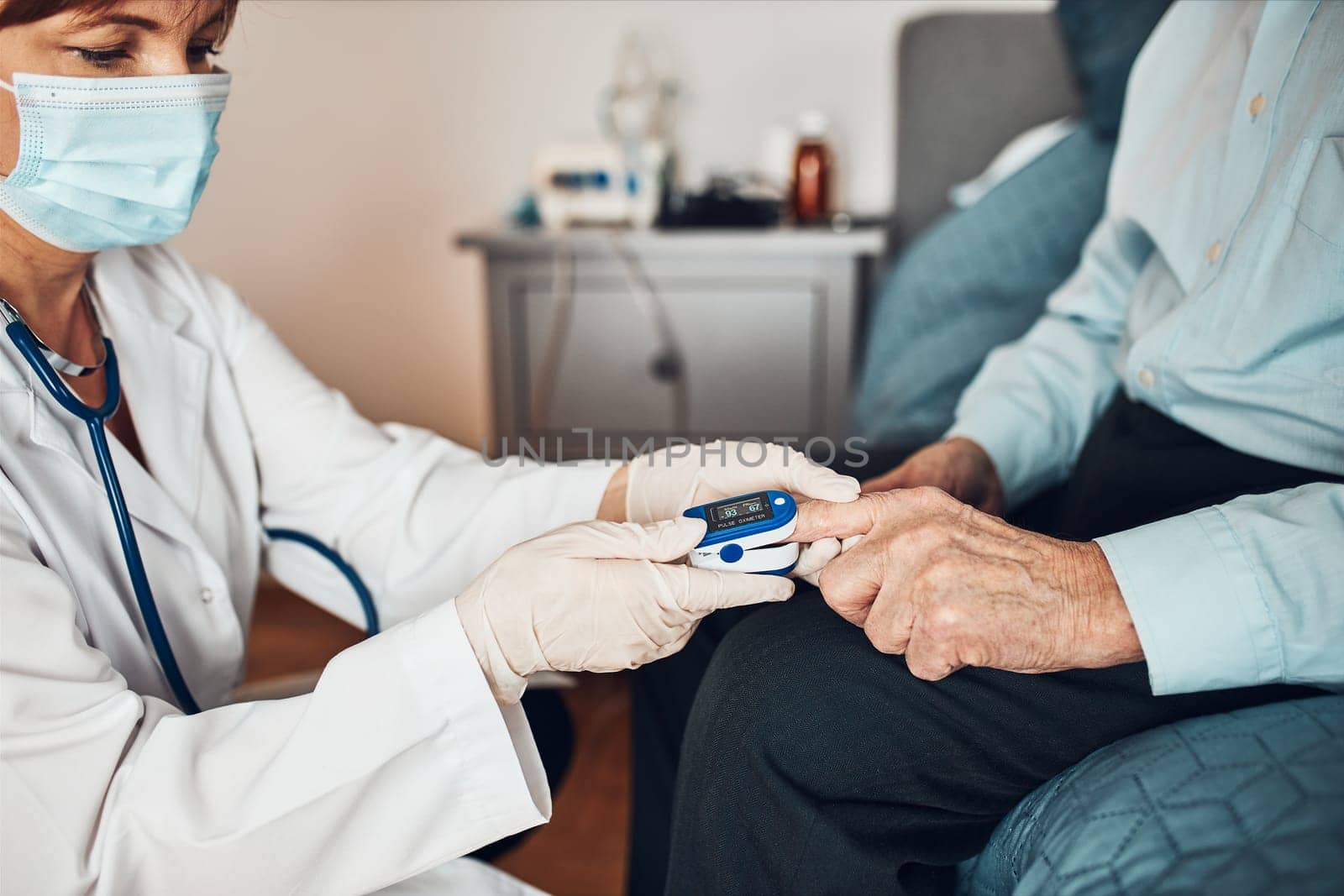Doctor measuring the degree of oxygen saturation of the blood and heart rate of senior patient using pulse oximeter. Home treatment of virus. Checking health condition. Coronavirus pandemic. Covid-19 outbreak