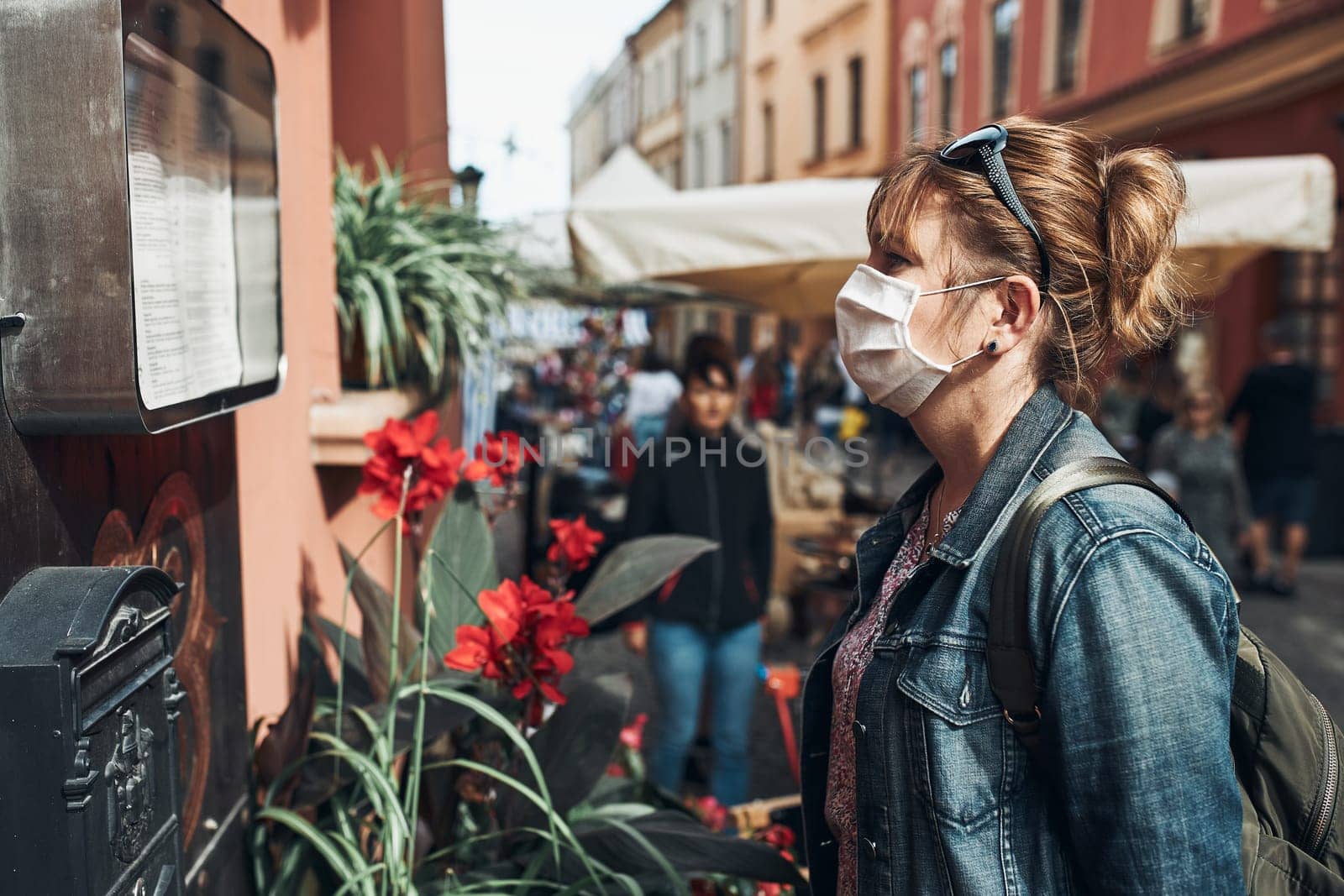Young woman standing in a street downtown looking to the side wearing the face mask to avoid virus infection and to prevent the spread of disease in time of coronavirus