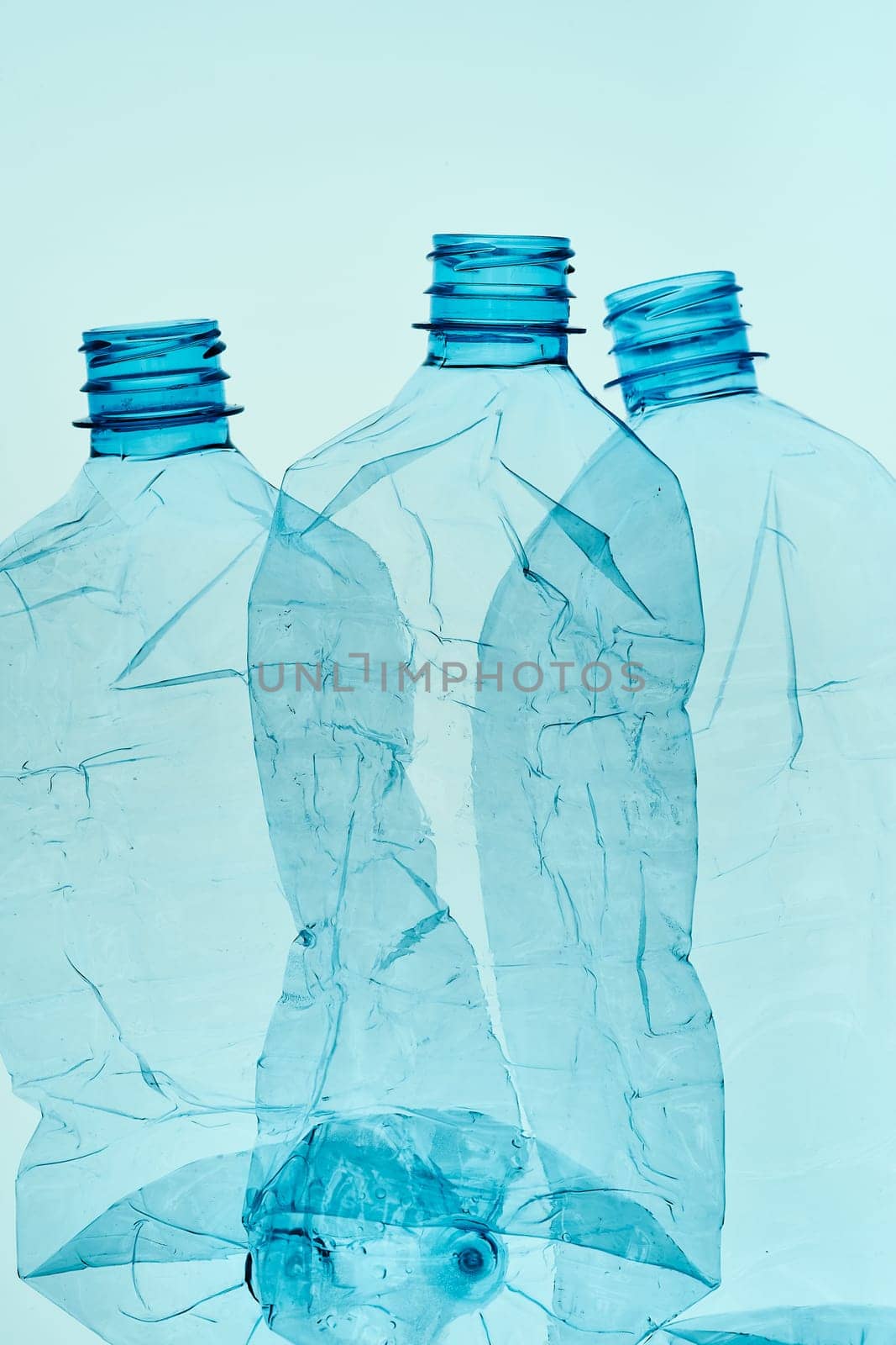 Empty plastic squashed bottles over blue background. Collecting plastic waste to recycling. Concept of plastic pollution and too many plastic waste. Copy space for text