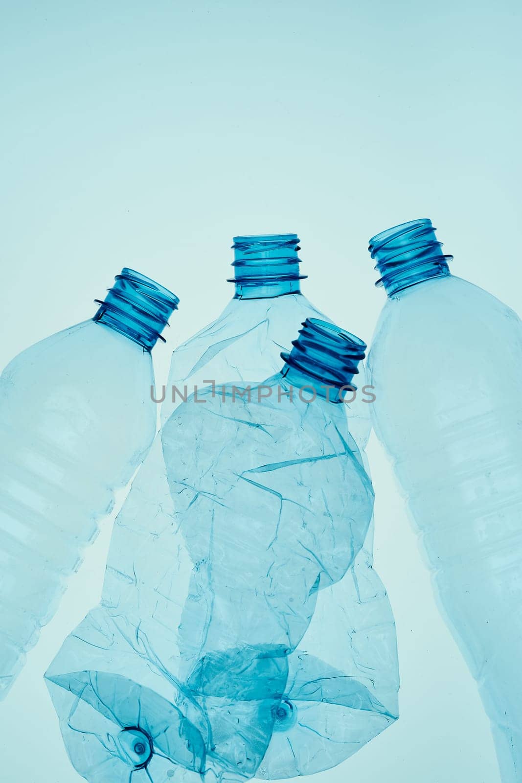 Empty plastic squashed bottles over blue background. Collecting plastic waste to recycling. Concept of plastic pollution and too many plastic waste. Copy space for text
