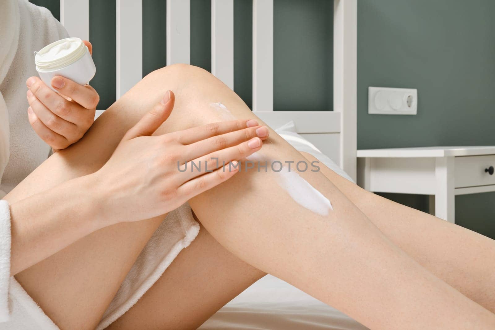 Closeup view of spreading cream on legs after shower