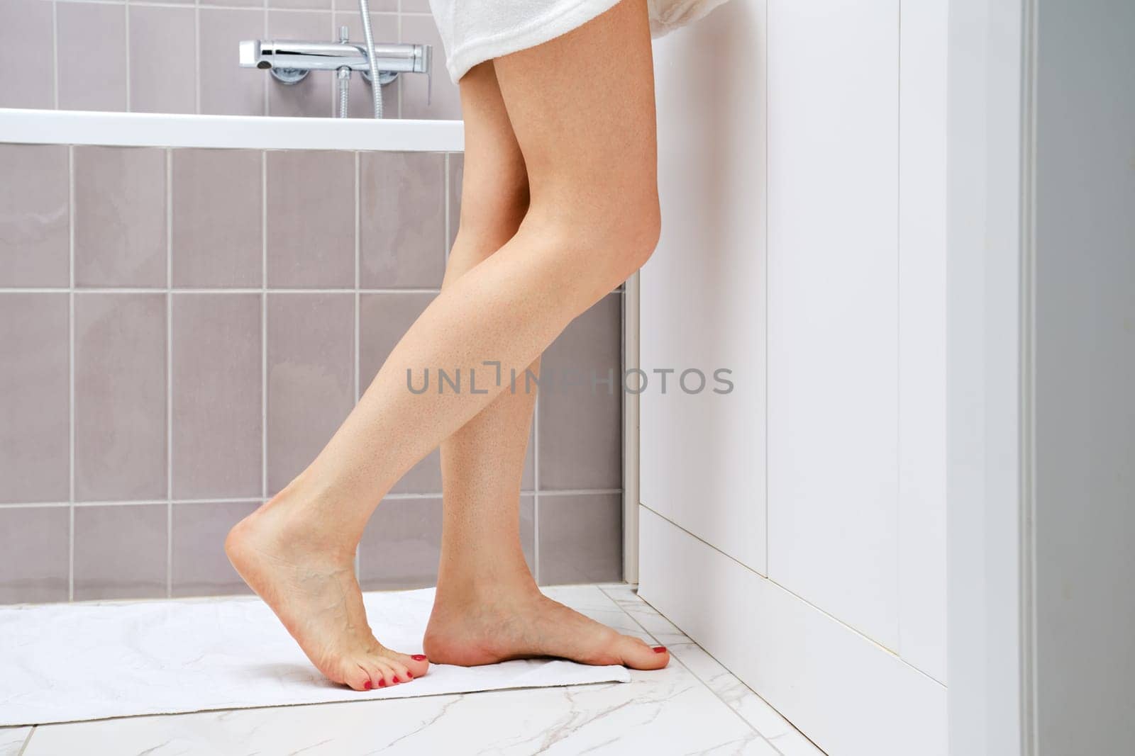 Cropped image of female legs standing in profile in bathroom