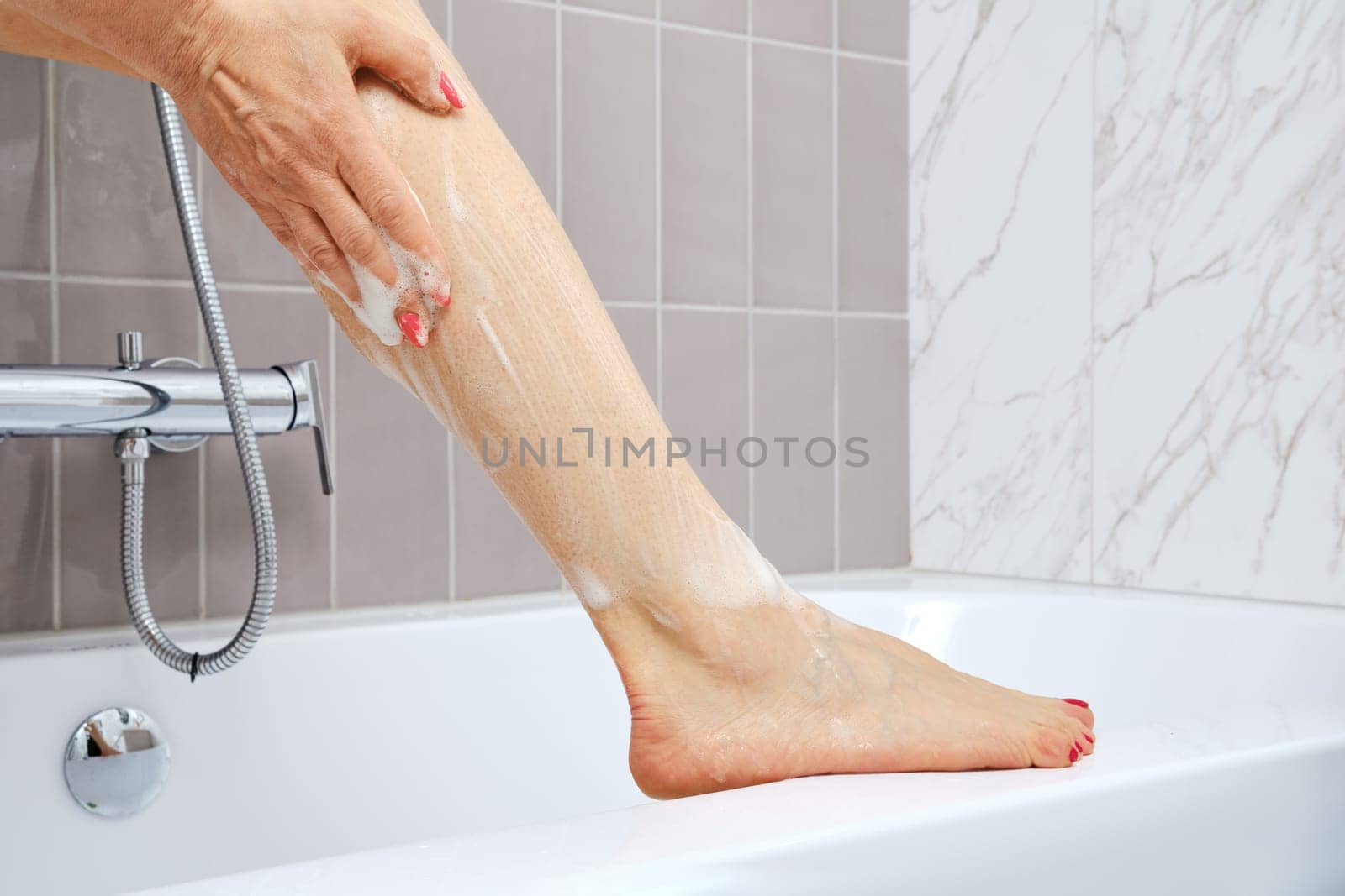 Unrecognizable senior woman washing her feet in bathtub