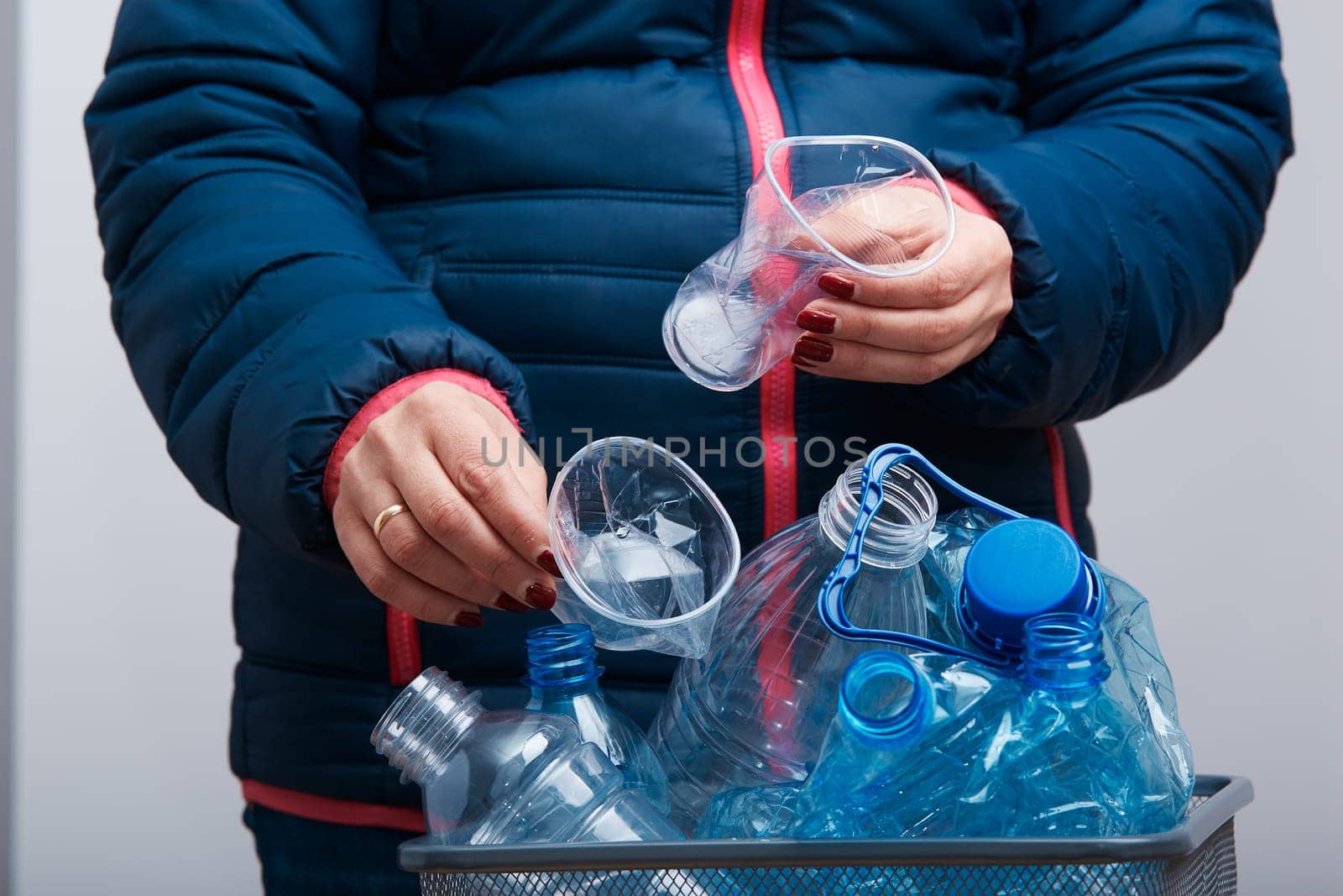 Woman throwing out used plastic bottles and packagings in trash bin. Collecting empty plastic squashed bottles in blue bag. Plastic waste to recycling. Concept of plastic pollution and too many plastic waste