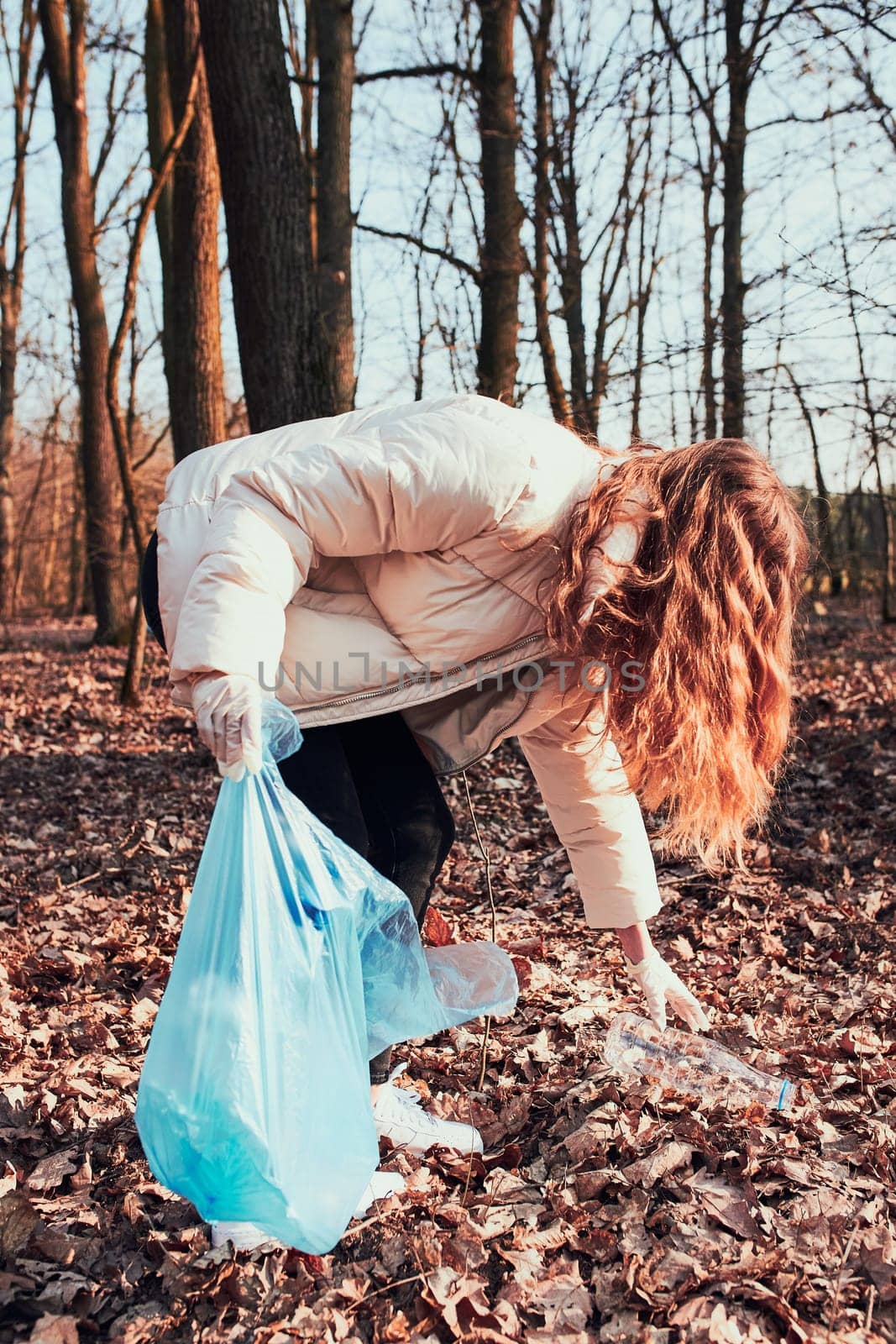Young woman cleaning up a forest. Volunteer picking plastic waste to bags. Concept of plastic pollution and too many plastic waste. Environmental issue. Environmental damage. Responsibilitiy for environment. Real people, authentic situations