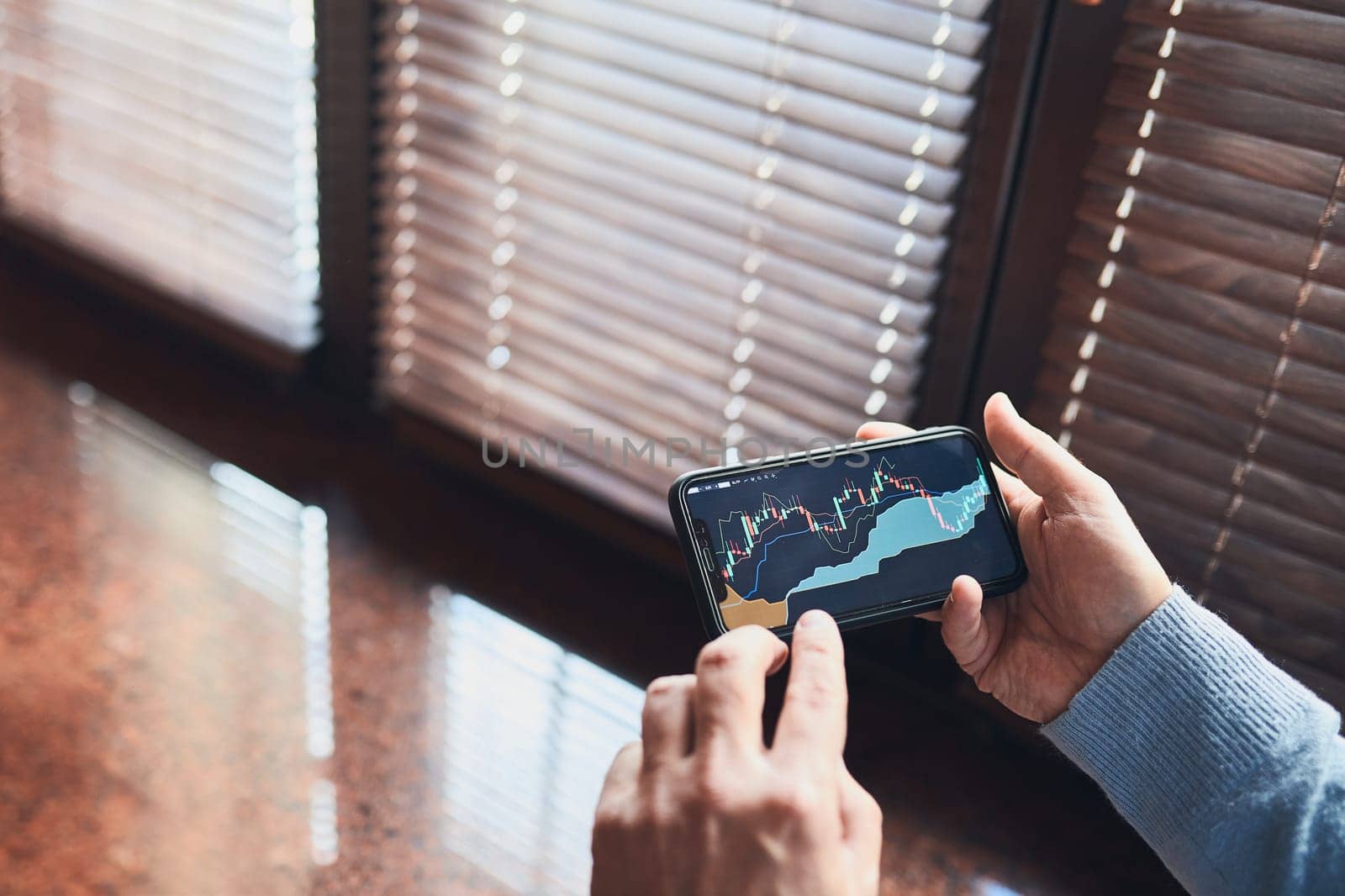 Person investing trading on stock cryptocurrency market using investing application on smartphone. Stock market investment in hand. Trader holding mobile phone looking at candle chart