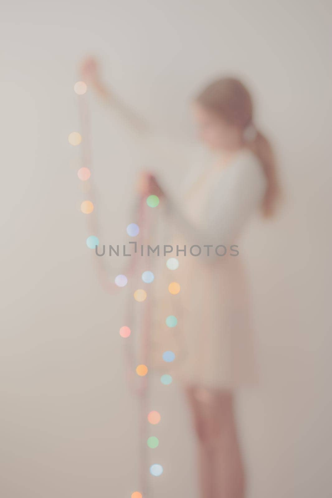 Out of focus portrait of young girl unwrapping colorful Christmas lights