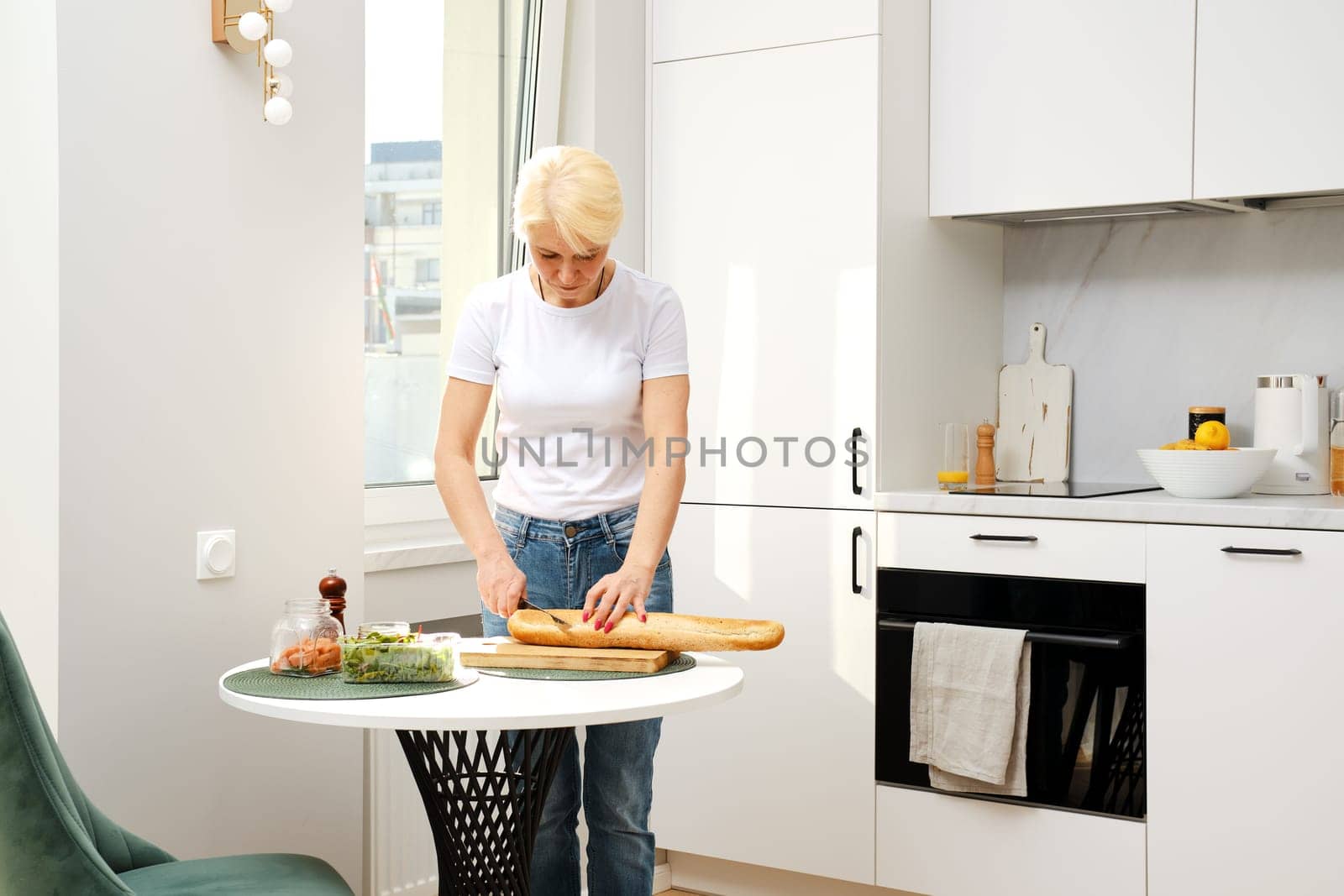Middle aged woman cuts fresh baguette on slices