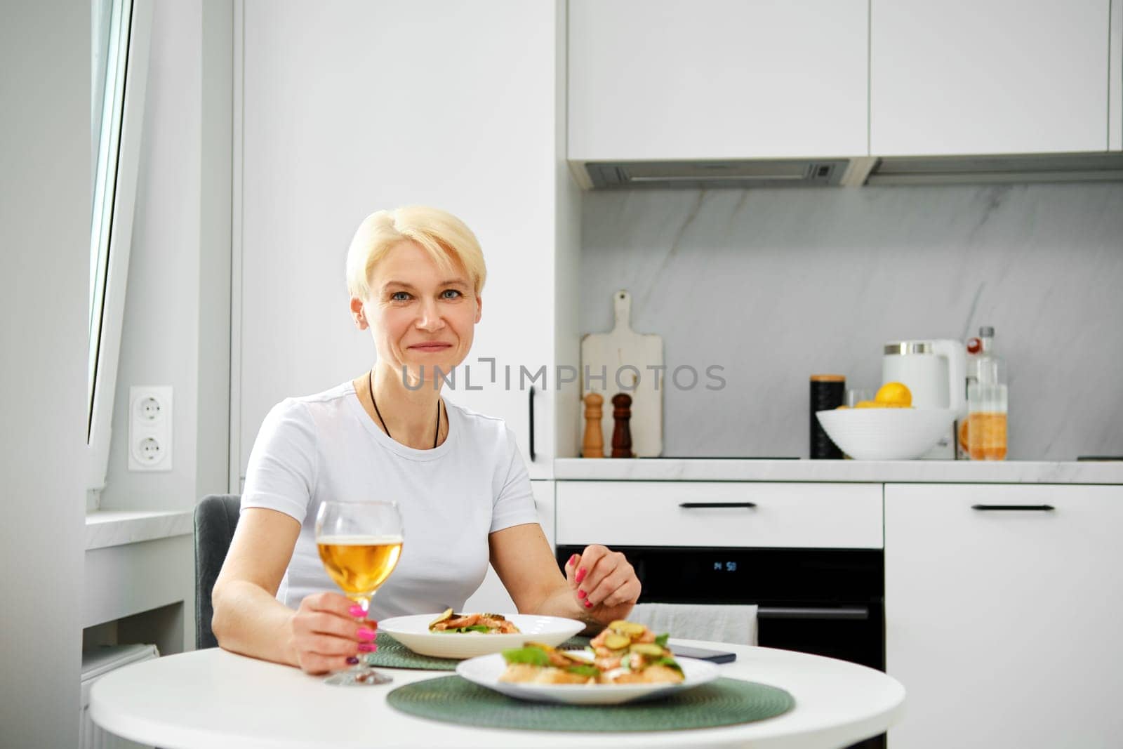 Portrait of positive senior woman in the kitchen having breakfast