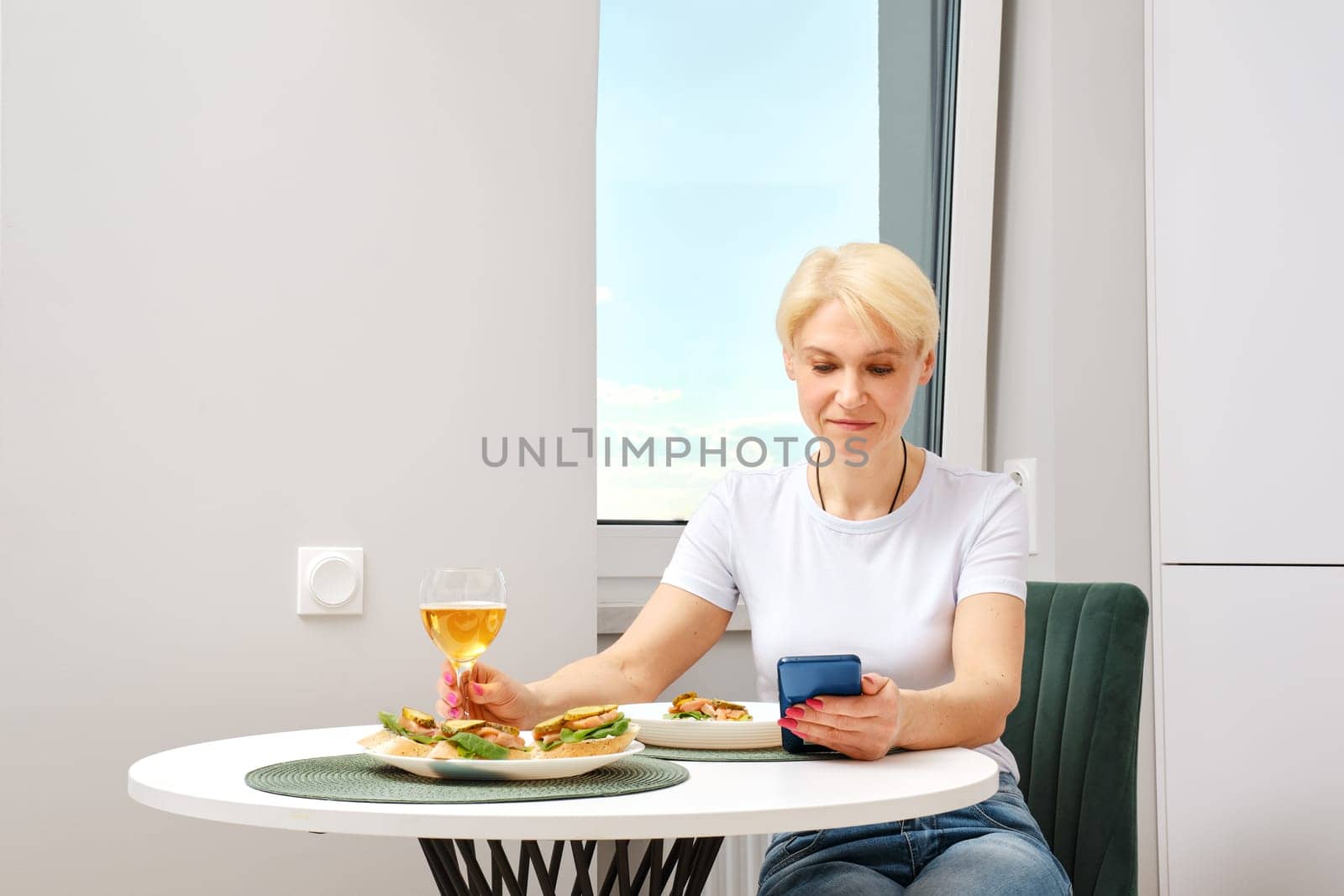 Senior woman reading morning news from smartphone while having breakfast