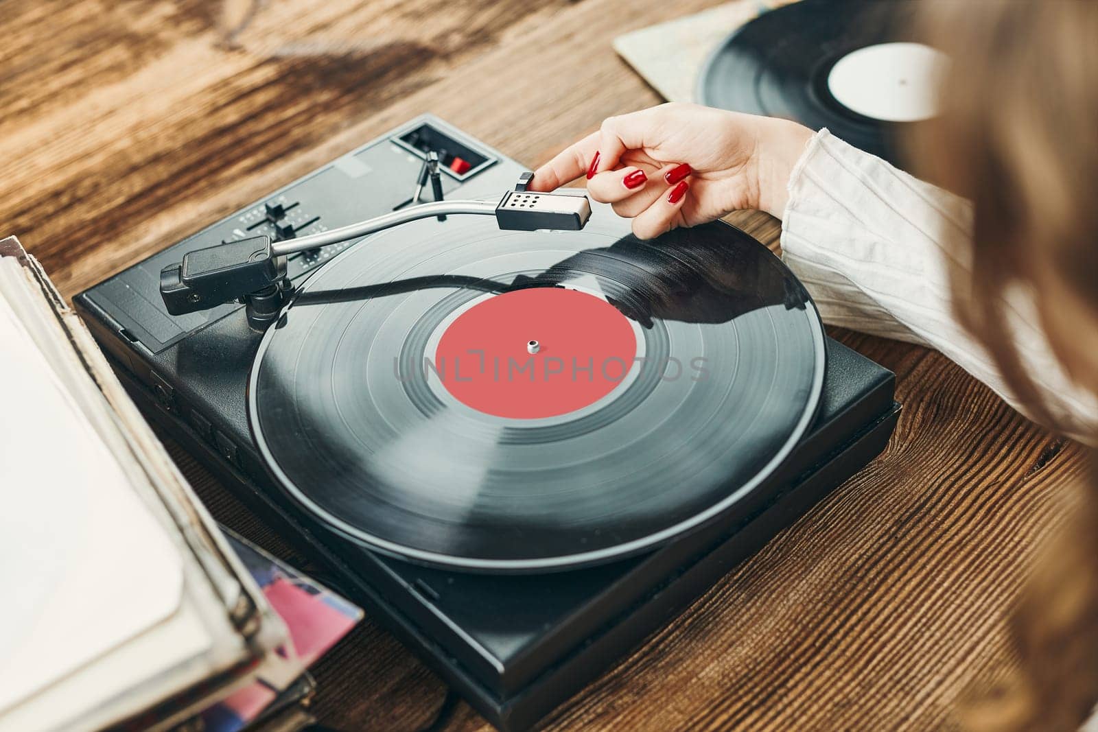 Young woman listening to music from vinyl record player. Playing music on turntable player. Female enjoying music from old record collection at home. Stack of analog vinyl records. Retro and vintage music style. Music Passion and hobby