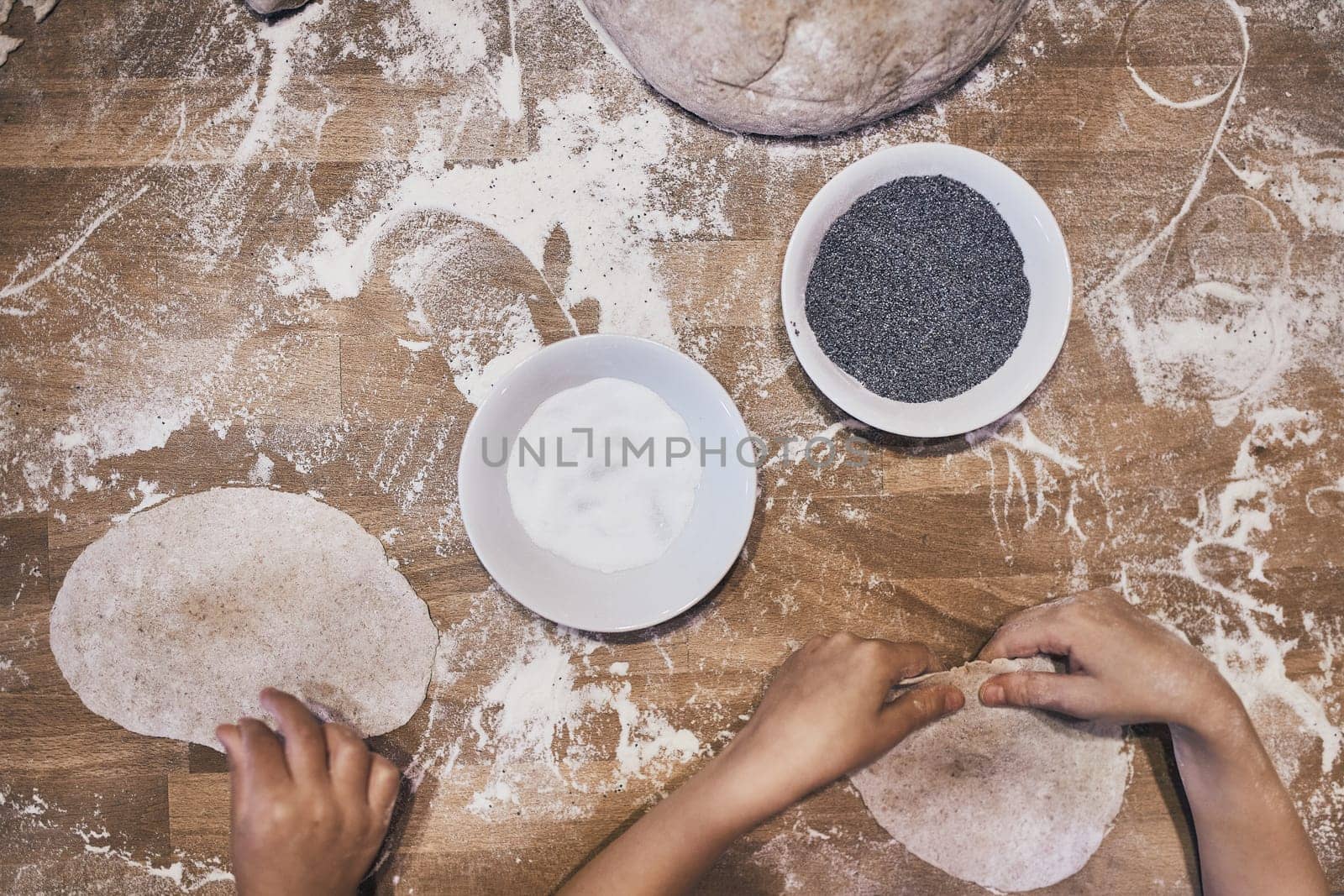 Hands kneading dough. People making dough for bread during bread making workshop. Flour and raw dough on wooden table