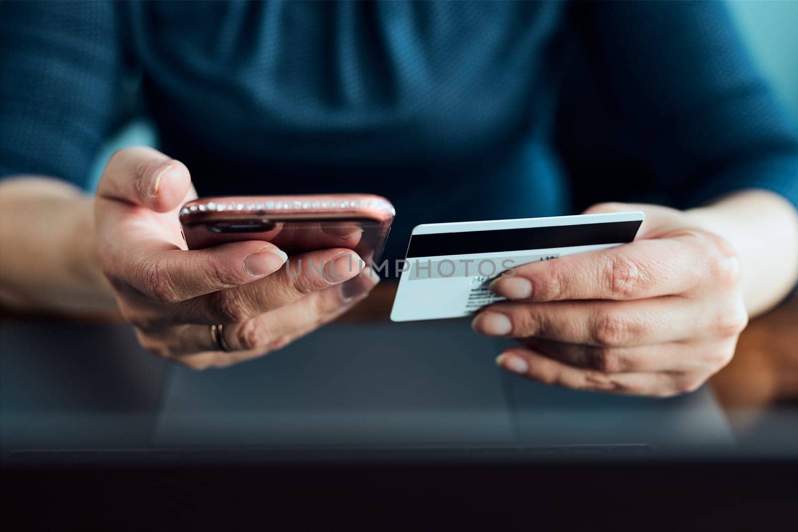 Woman doing online shopping using debit card and laptop. Female hands holding credit card over a keyboard of laptop sitting at a desk buying goods online from home