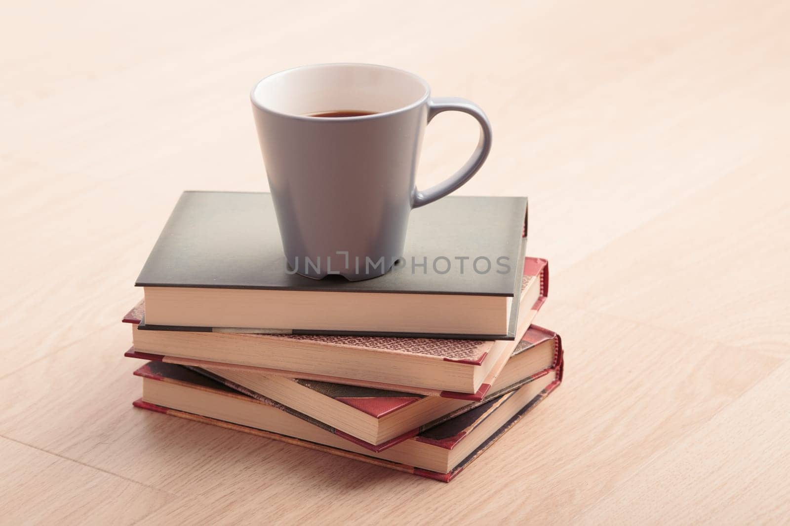 A few books with cup of coffee on wooden floor