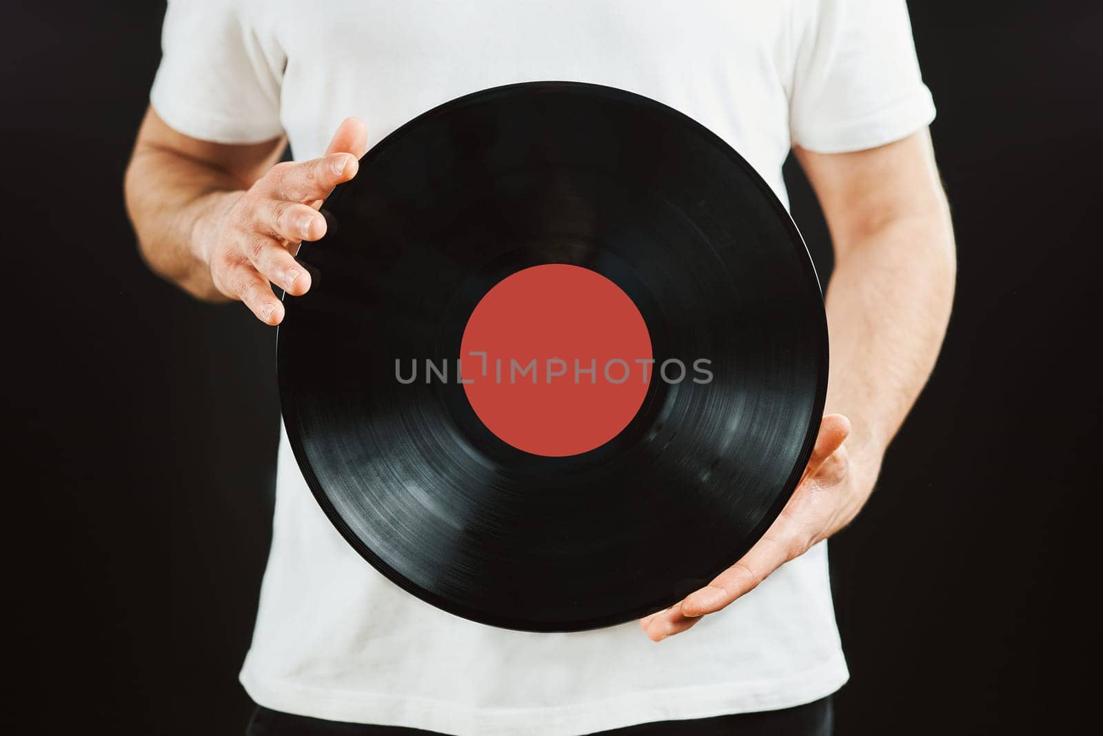 Man with vinyl record. Vintage music style. Male holding black analog disk standing on black background. Retro music. Classic audio