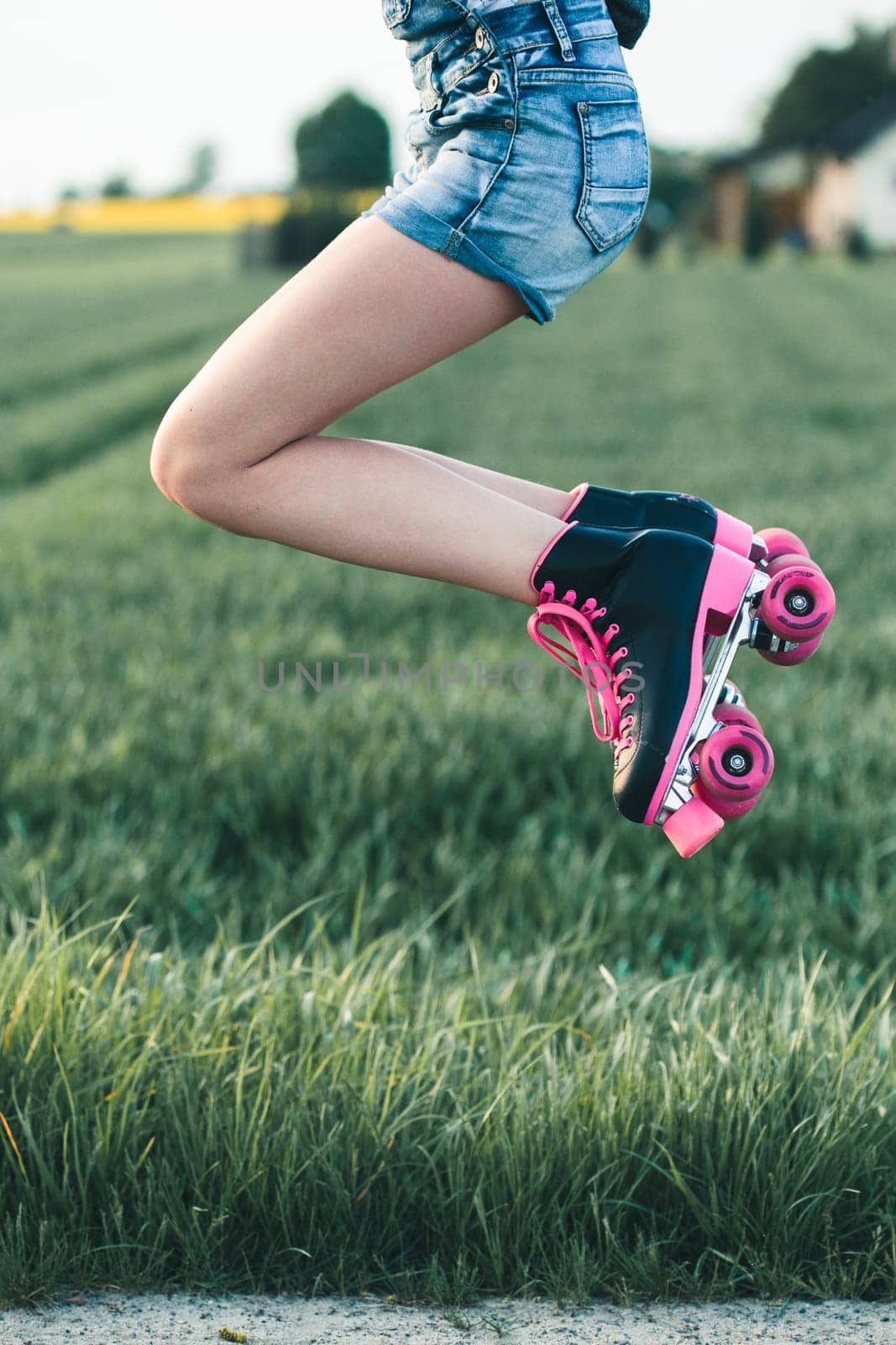 Teenage girl having fun rollerskating, jumping, spending time on summer day