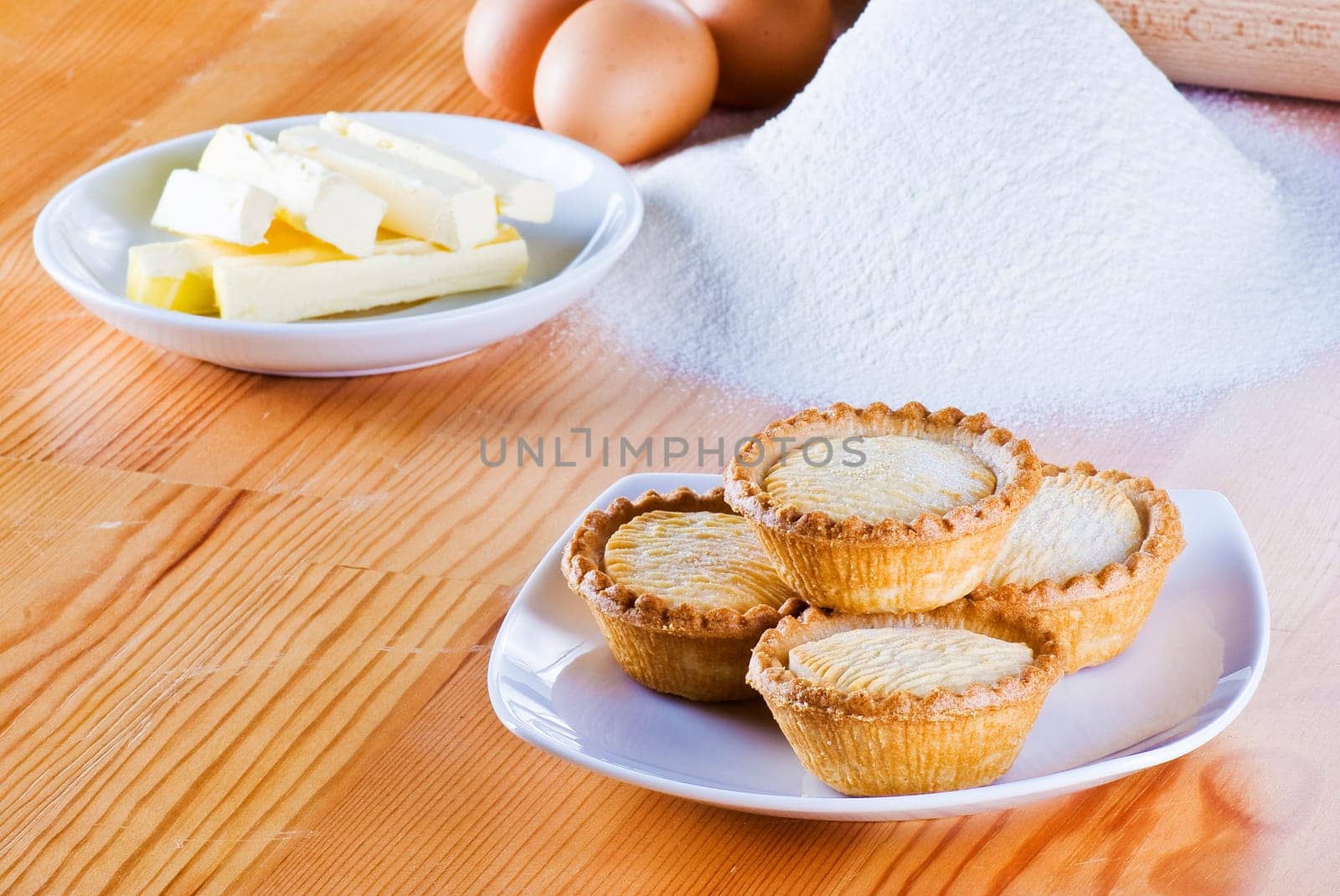 Freshly made apple pies on the table with flour eggs and butter
