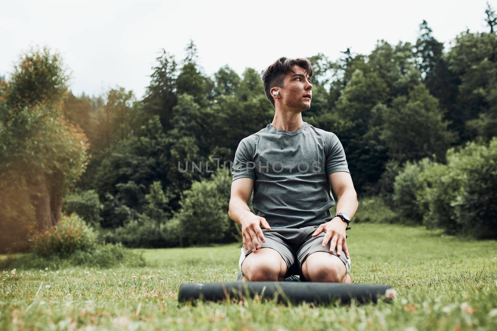 Young man doing exercises outside on grass during his calisthenics workout. Teenager training outdoors