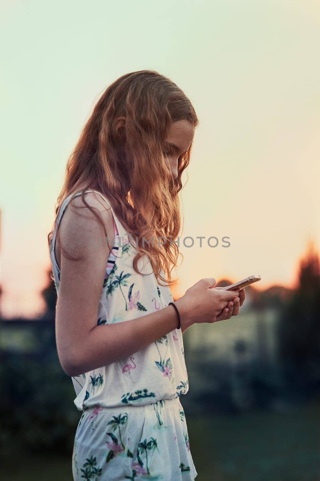Young woman using mobile phone smartphone standing in a backyard. Candid people, real moments, authentic situations