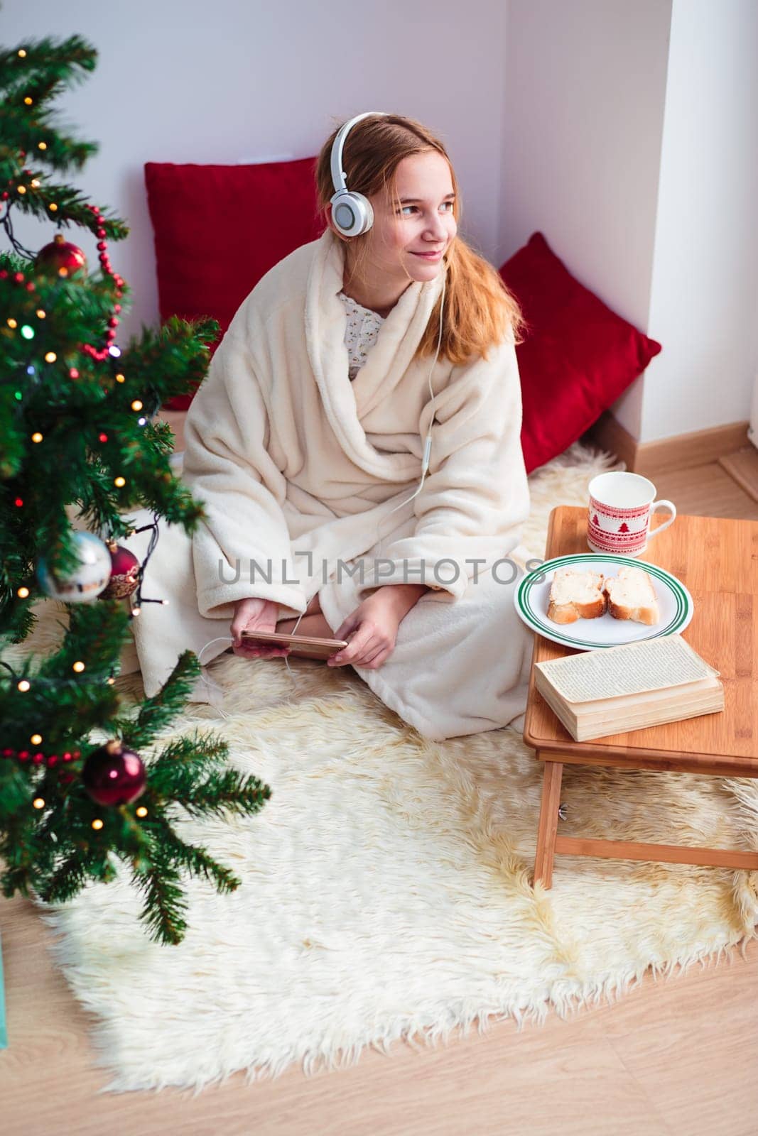 Young girl listening to Christmas carols through her headphones in the early morning