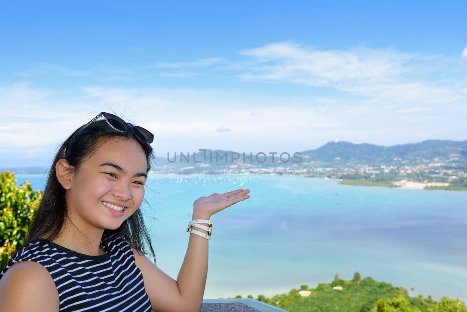 Women tourist smiling are happy to show his hand inviting them to see the beautiful landscape of sea on Khao-Khad mountain viewpoint famous attractions in Phuket Province, Thailand
