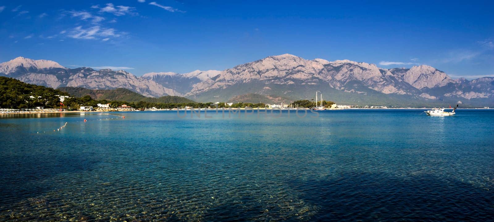 Kemer Antalia nice view of the sea. Beach Kemer Antalia with sand and mountains, the sea with the ship. Beautiful harbor near the sandy beach.