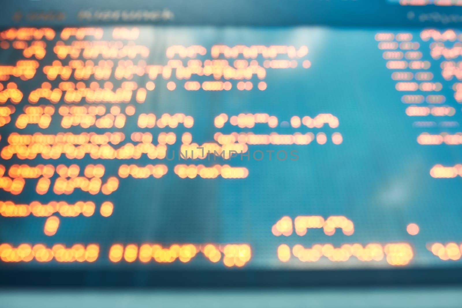 Out of focus blurred display screen with orange digital characters and letters. Digital background