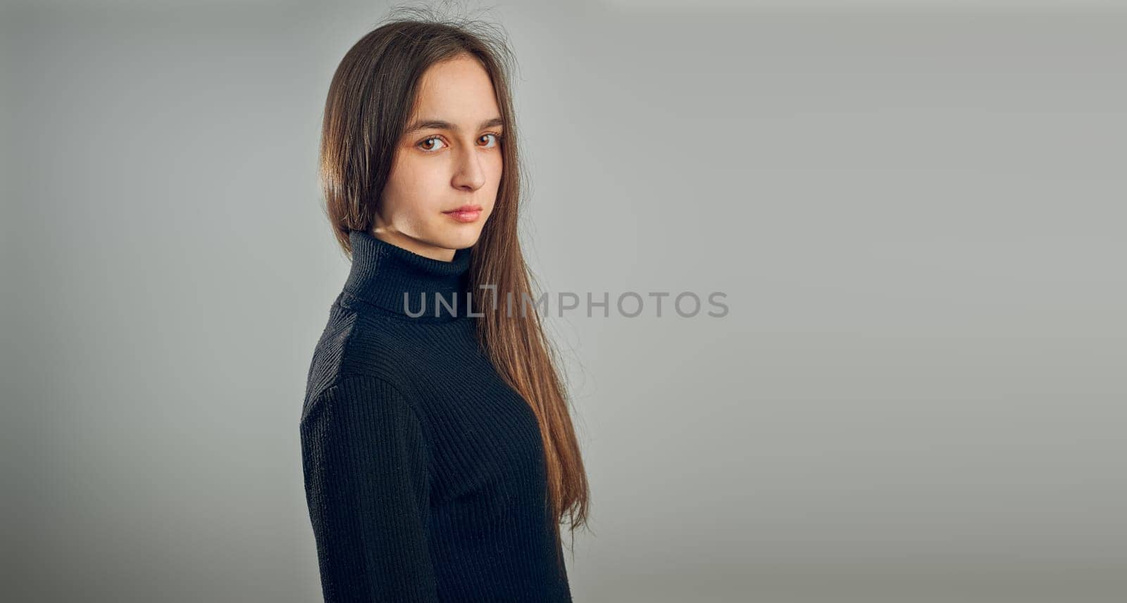 Portrait of young woman. Classic portrait in positive mood, beautiful model posing in studio over plain background looking at camera