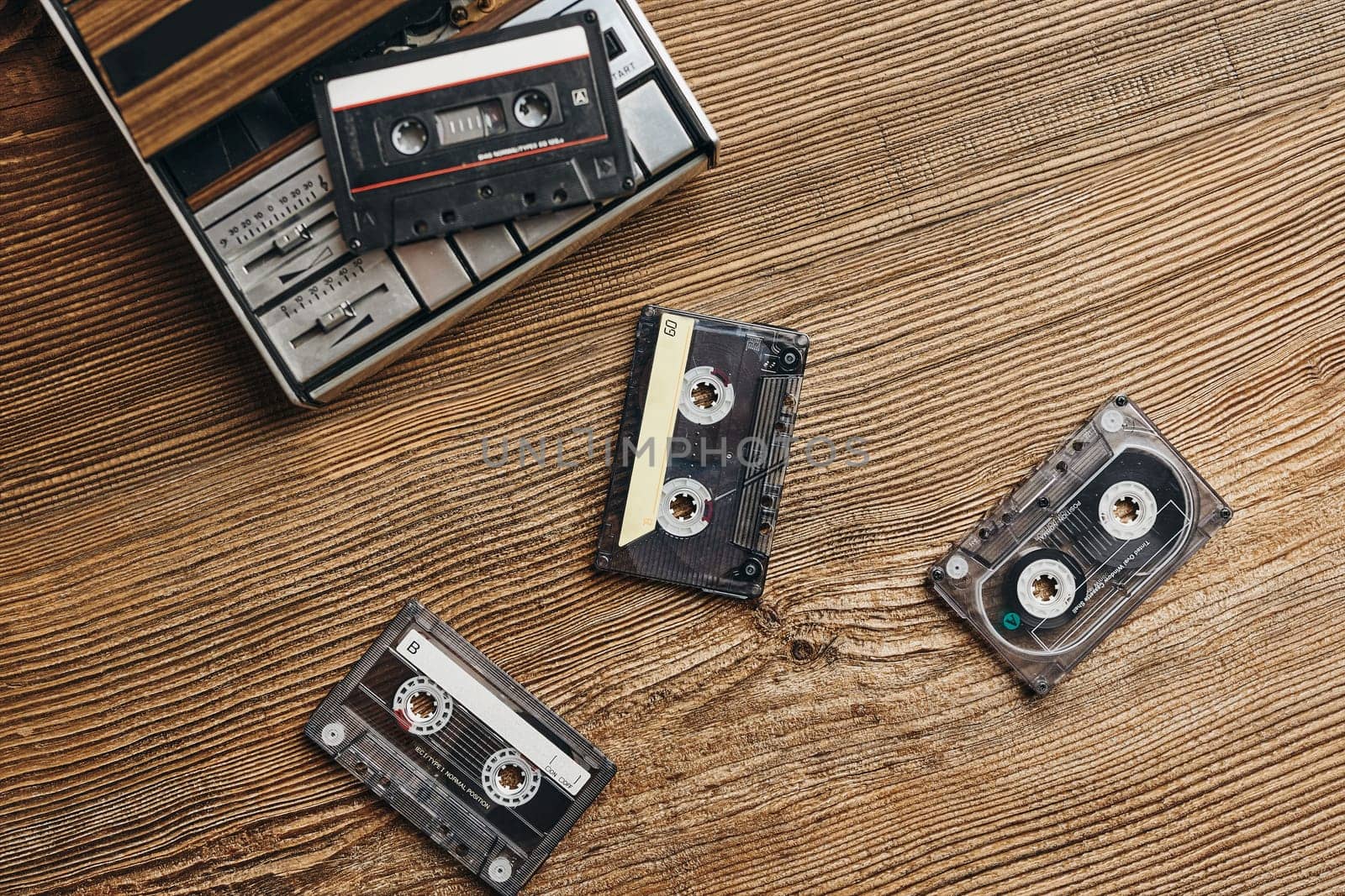 Compact cassette tapes and cassette recorder on wooden table. Retro music style. 80s music party. Vintage style. Analog equipment. Stereo sound. Back to the past