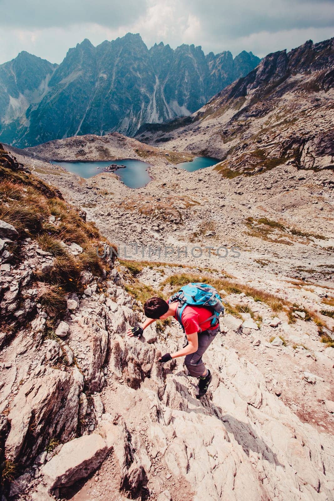 Young man hiking alone along a rocky trail in the mountains