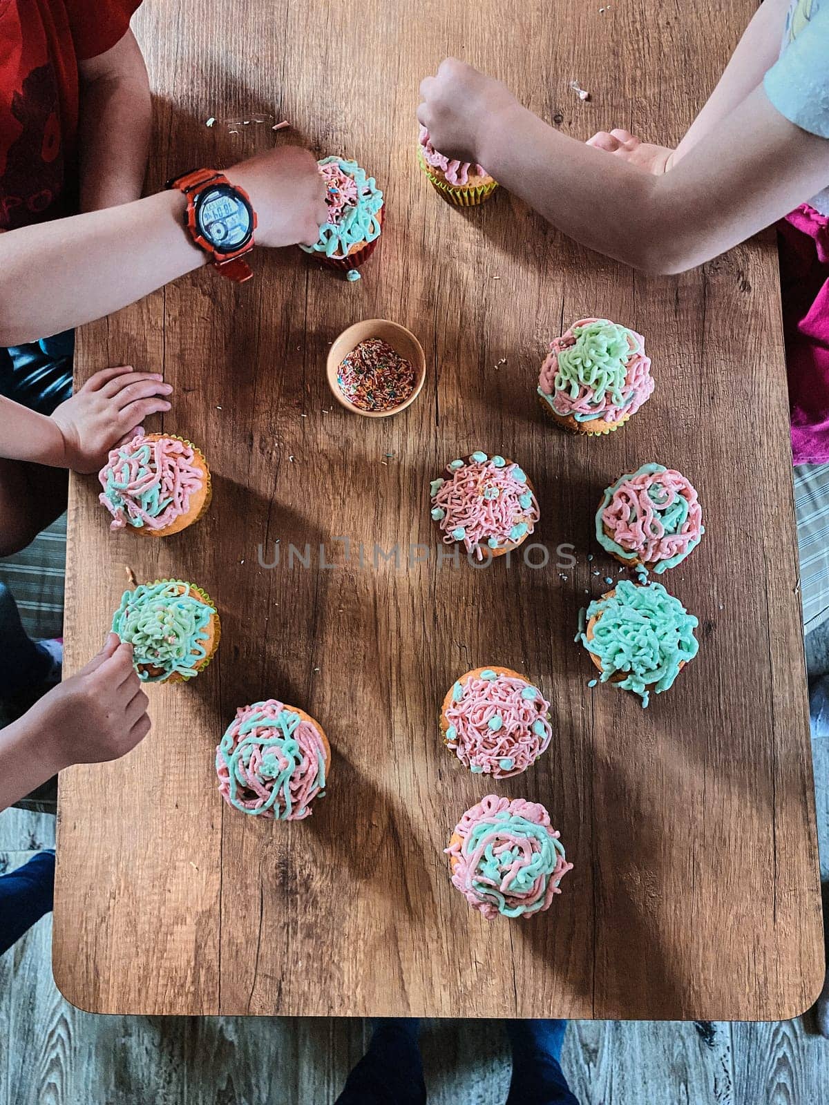 Group of children baking cupcakes, preparing ingredients, topping, sprinkles for decorating cookies. Kids cooking, working together in kitchen at home. Concept of happy family