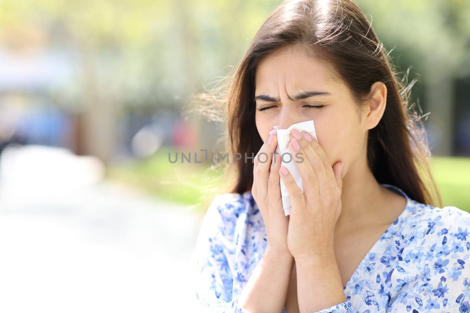 Ill woman blowing or coughing on tissue in the street