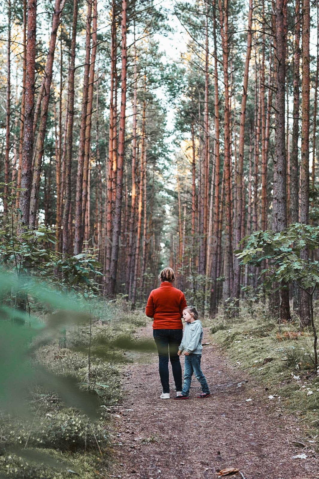 Mother and her little daughter walking in a forest during summer vacation trip. Family spending time together outdoors in nature