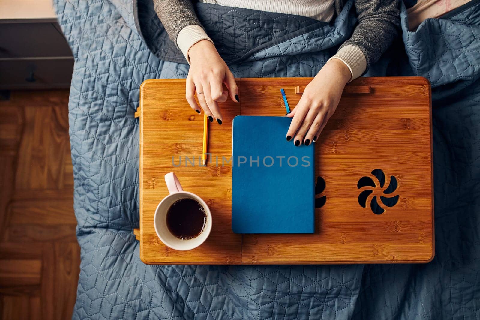Young woman opening diary, writing journal. Making notes in diary sitting in bed at home