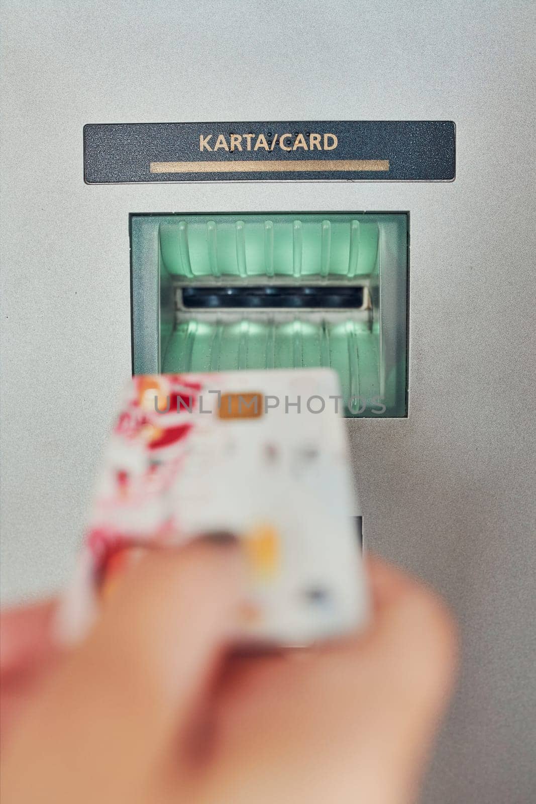 Woman withdrawing money from atm machine putting credit card into atm terminal. Close shot of femal hand holding bank card