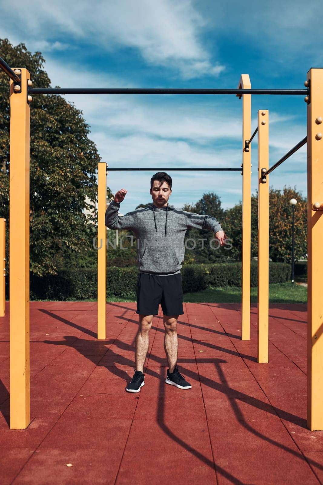 Young man stretching before his workout in a modern calisthenics street workout park. Man wearing sportswear