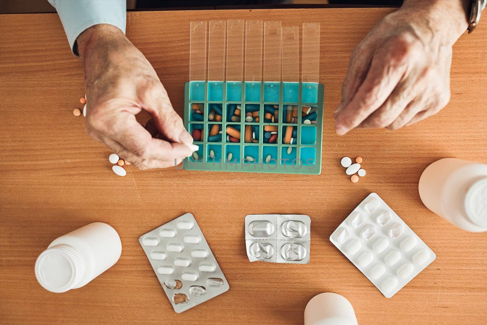 Senior man organizing his medication into pill dispenser. Senior man taking pills from box. Healthcare and old age concept with medicines. Medicaments on table